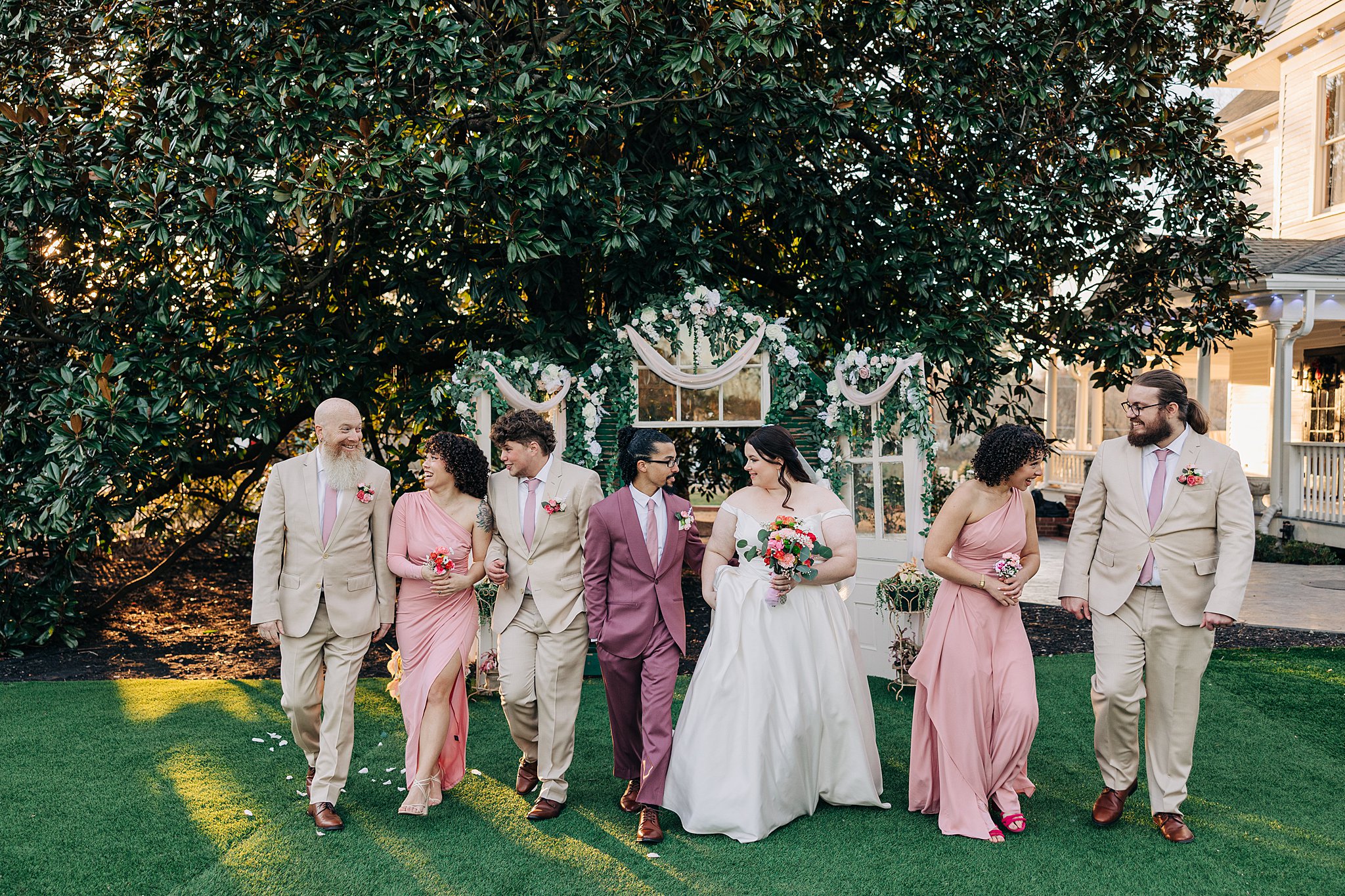 Newlyweds walk up the aisle on the lawn laughing with their wedding party