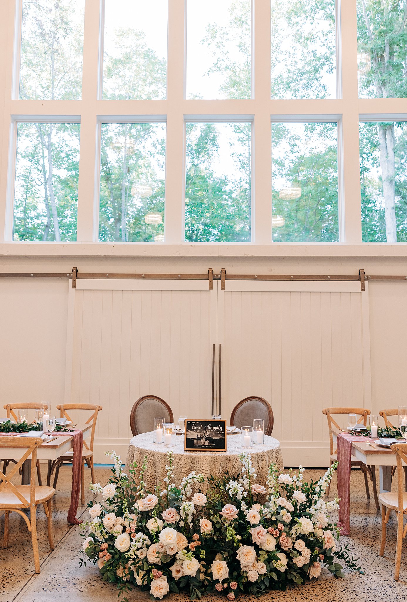Details of the newlywed's head table with a large floral arrangement at the carolina grove wedding venue