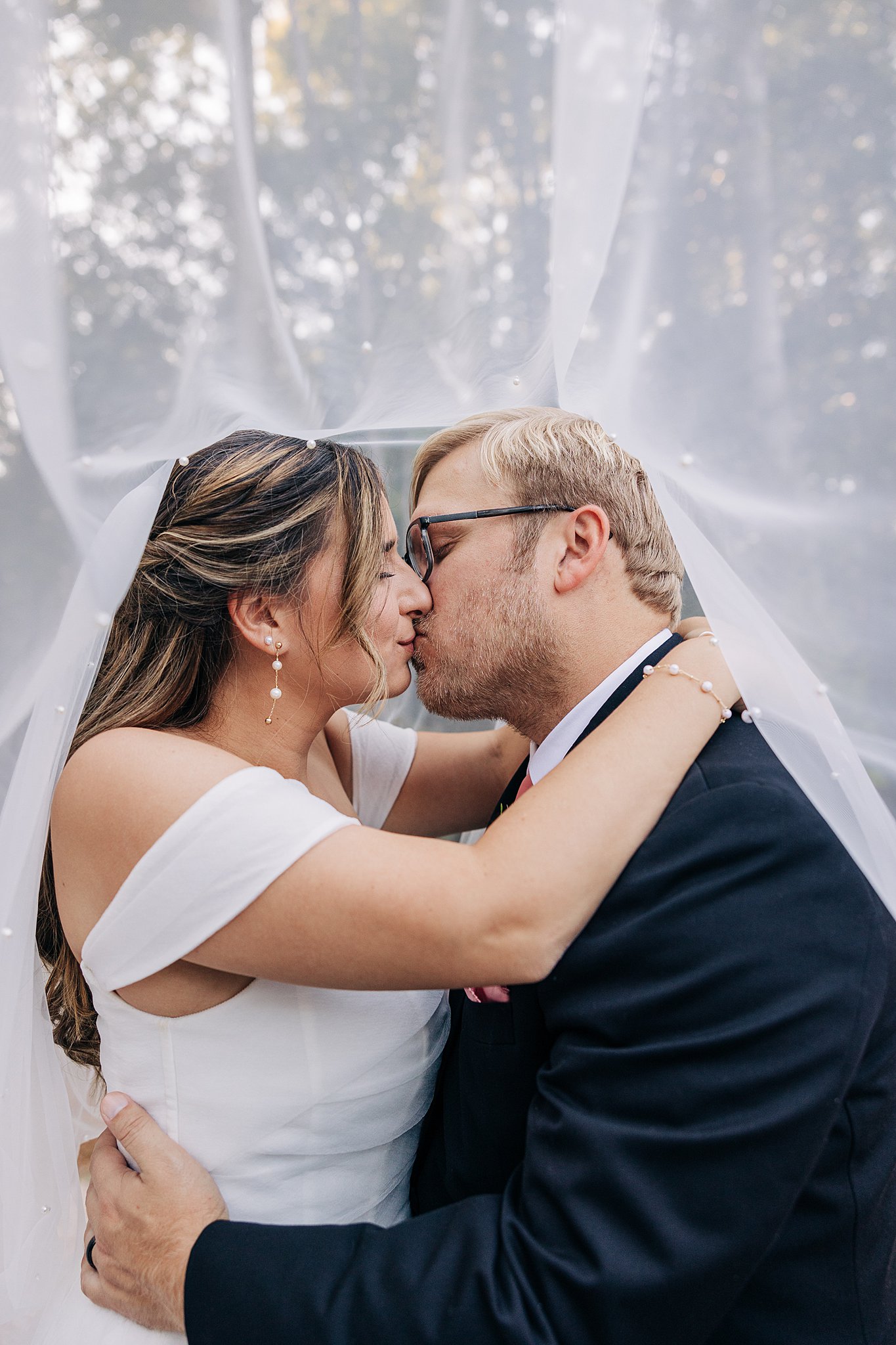 Newlyweds kiss under the veil at sunset