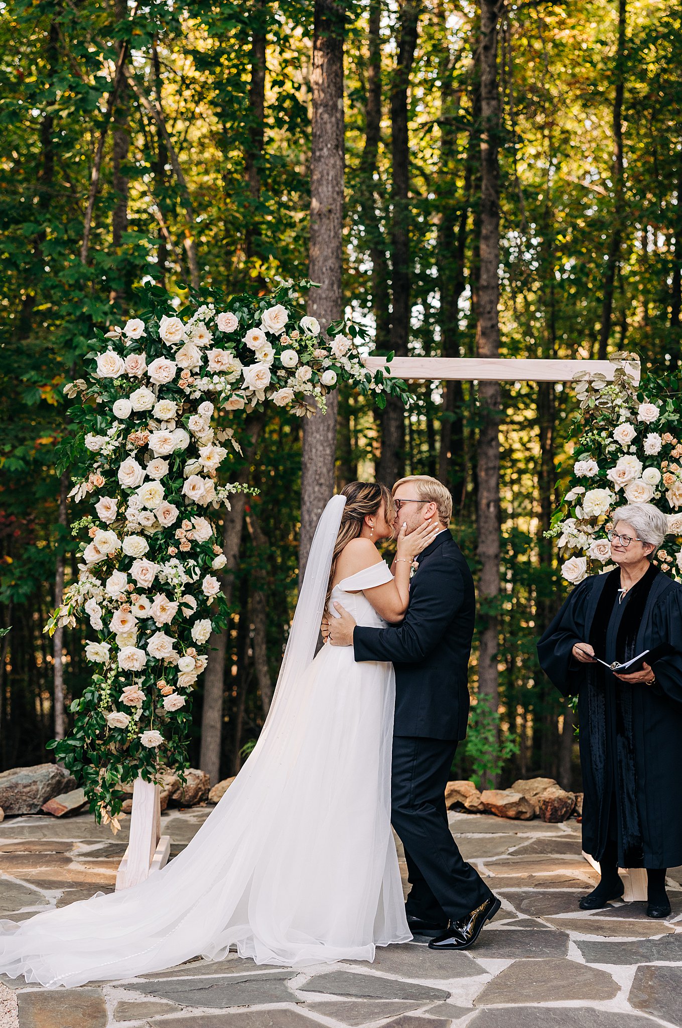 Newlyweds kiss under an outdoor arbor in the woofs to end their ceremony