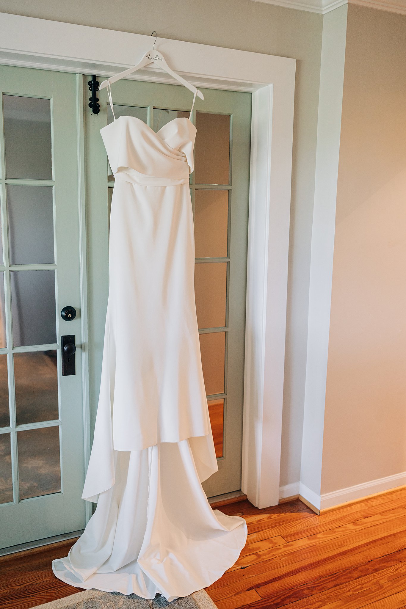 A white silk wedding dress hands in a doorway