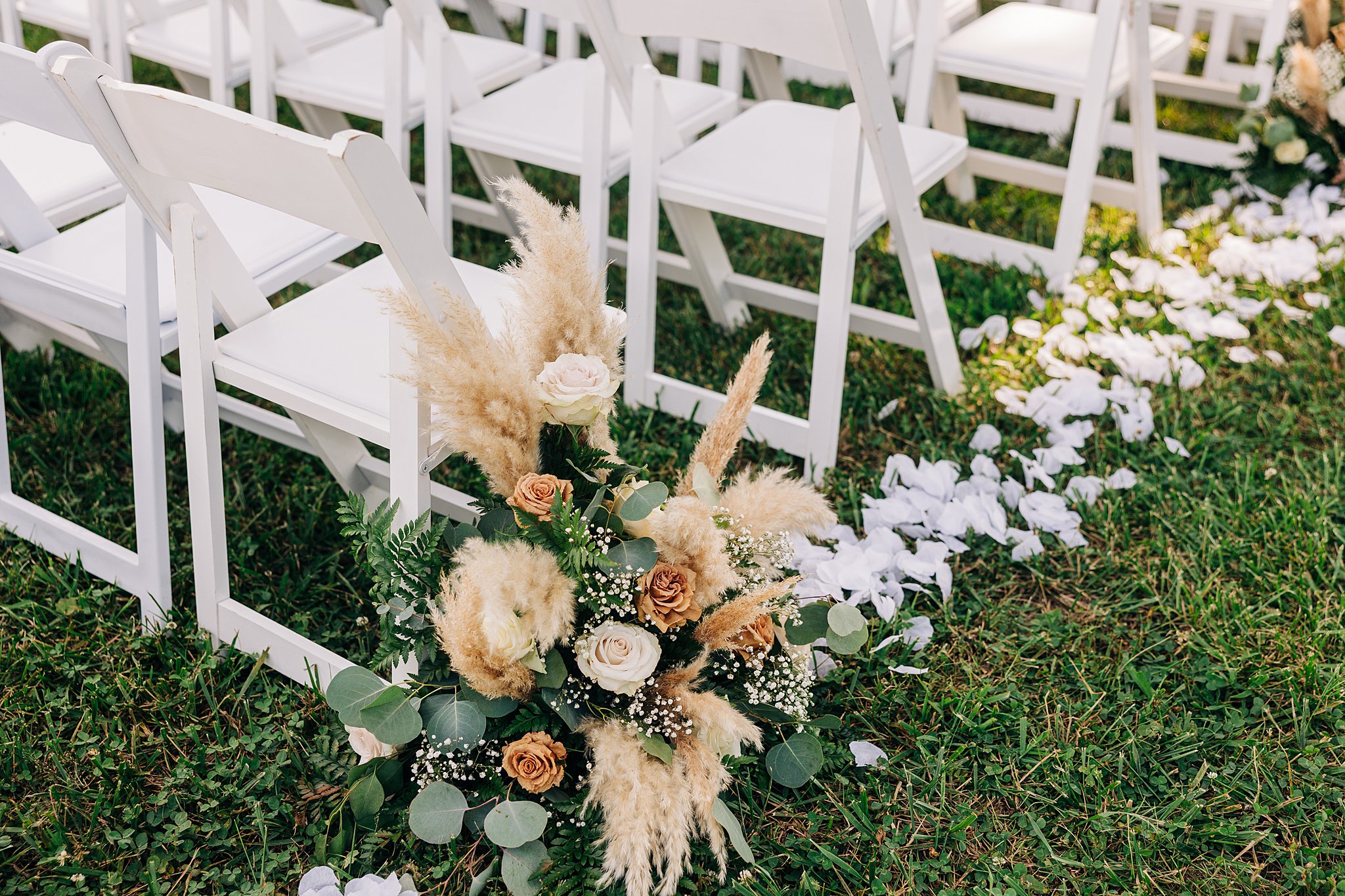 Details of a bouquet of flowers decorating the aisle of an outdoor wedding ceremony
