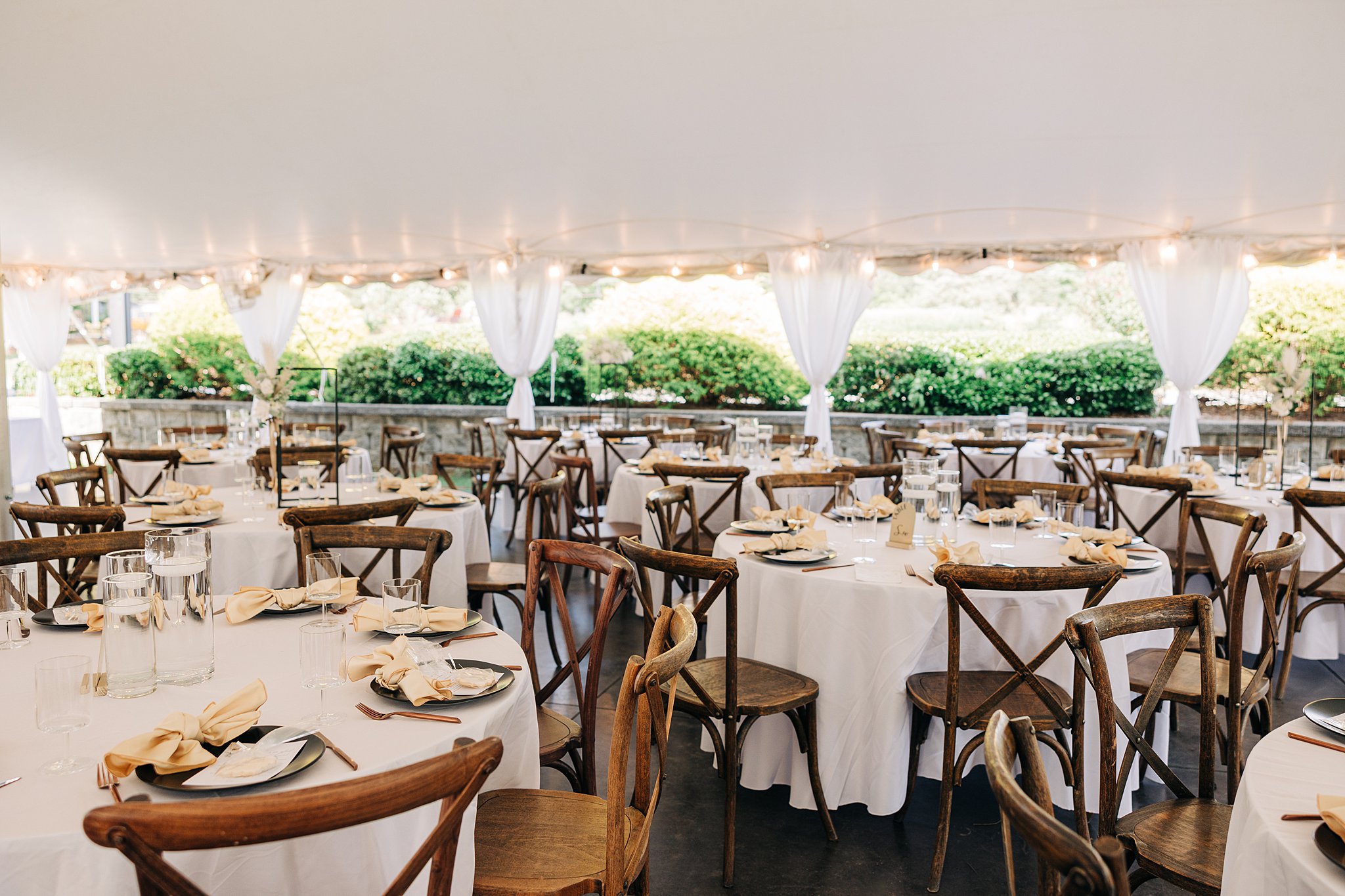 A wedding reception set up with wooden chairs and white linen at the Summerfield Farms wedding venue