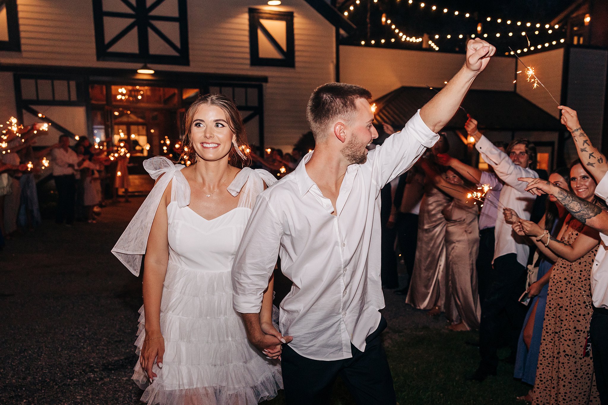 Newlyweds exit their Summerfield Farms wedding under sparklers while holding hands and celebrating