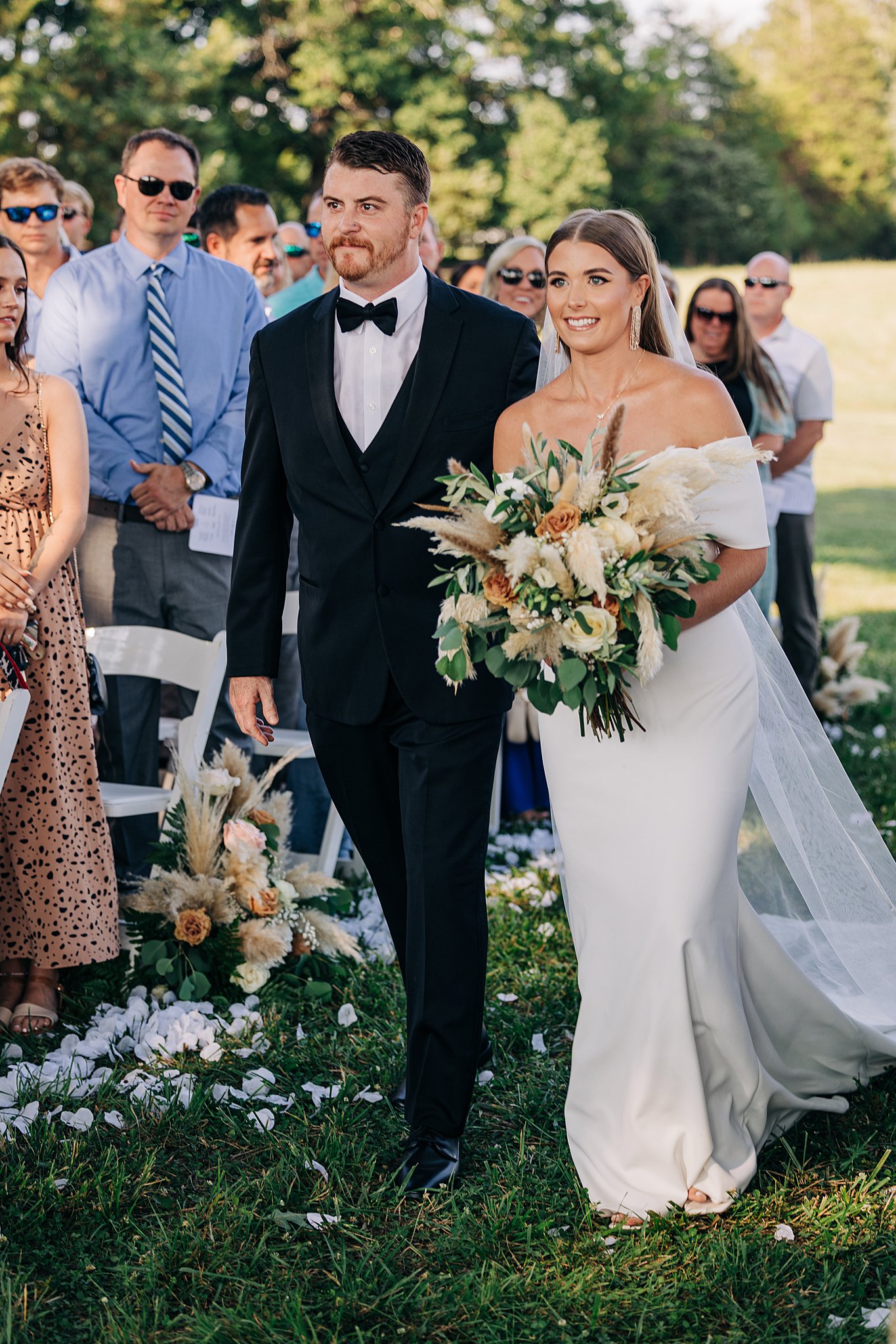 A man walks his sister down the aisle of her Summerfield Farms wedding