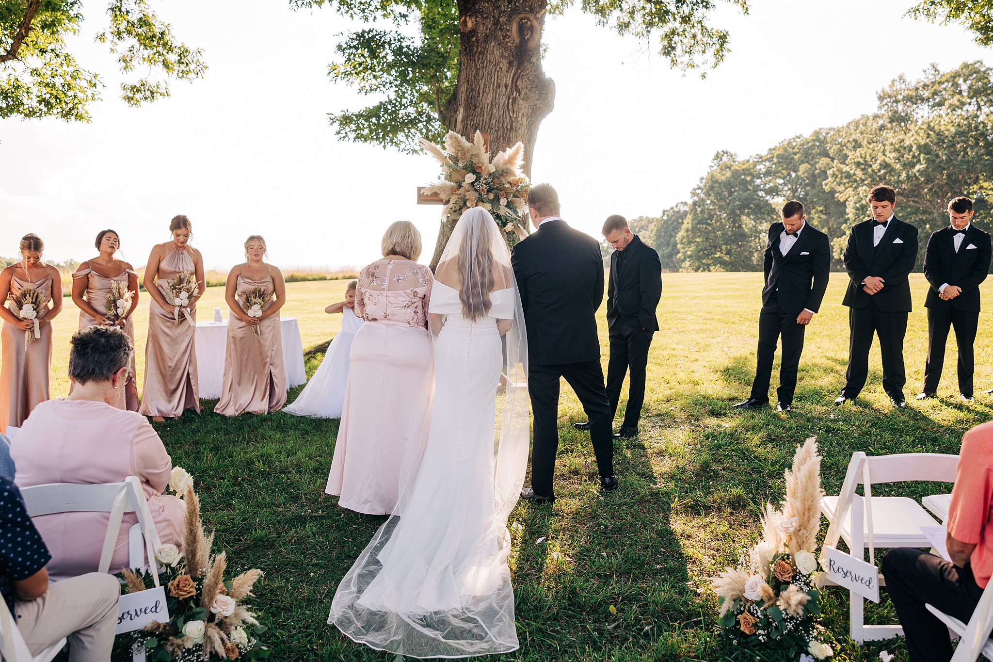 A bride arrives at the altar of her outdoor wedding ceremony with mom and brother at her Summerfield Farms wedding