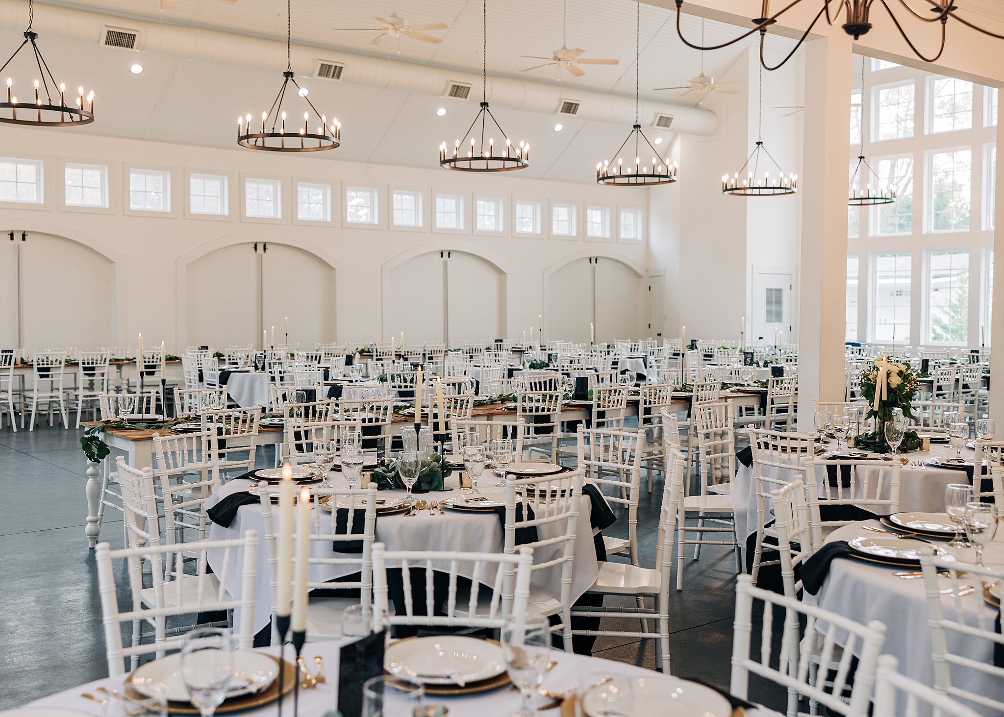 A view of a wedding reception set up with white chairs and linens