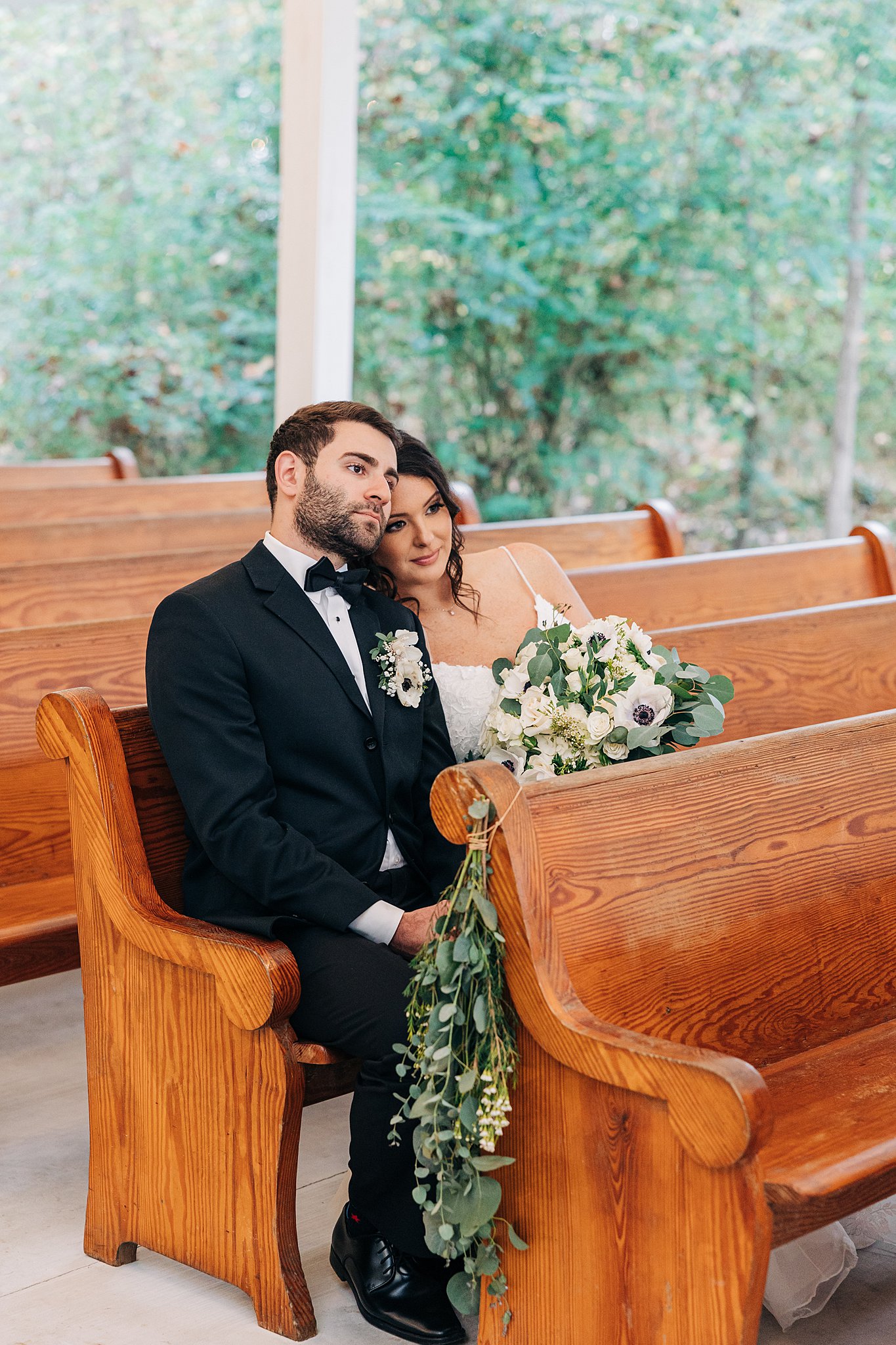 Newlyweds snuggle in a wooden pew at their cornealius properties wedding ceremony chapel