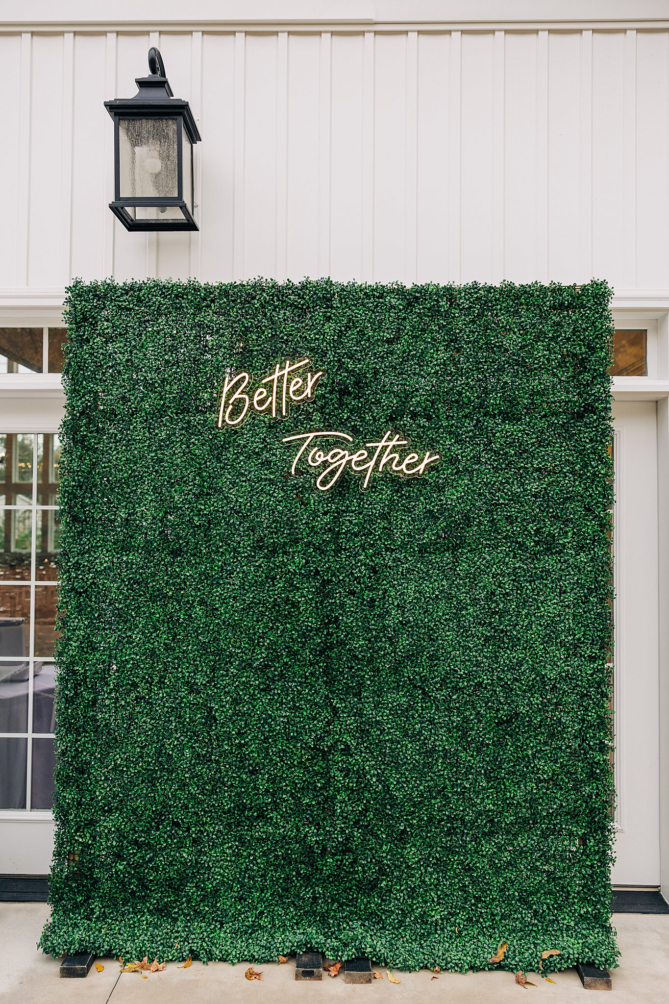 A greenery wall with an LED sign built into it outside a wedding venue