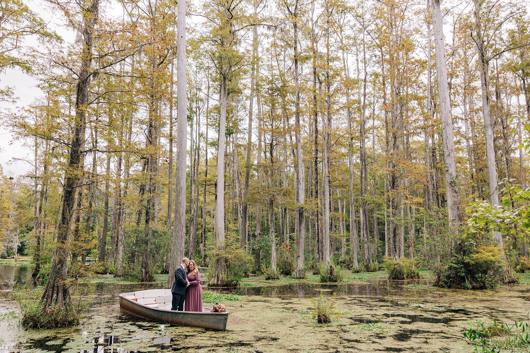 A couple stands in a boat floating in the cypress gardens wedding engagement venue