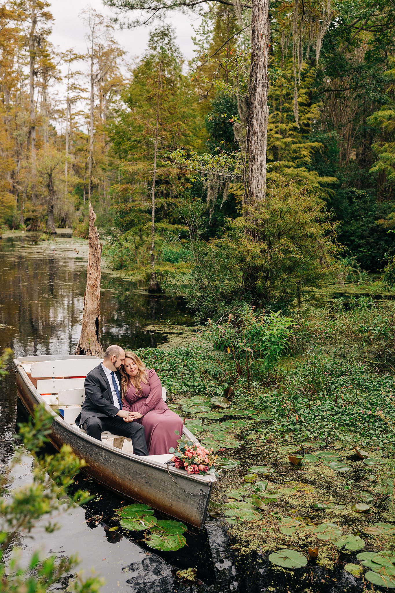 A peek at a couple snuggling while floating in a boat in a swamp