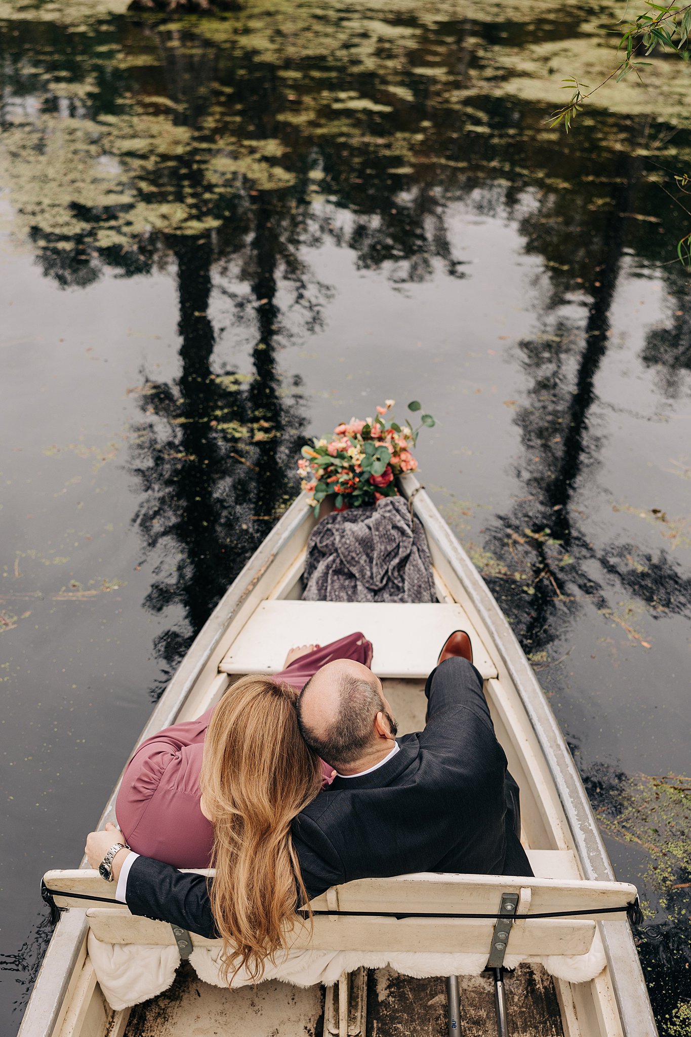 A newly engaged couple cuddle while exploring a swamp for their cypress gardens wedding engagement