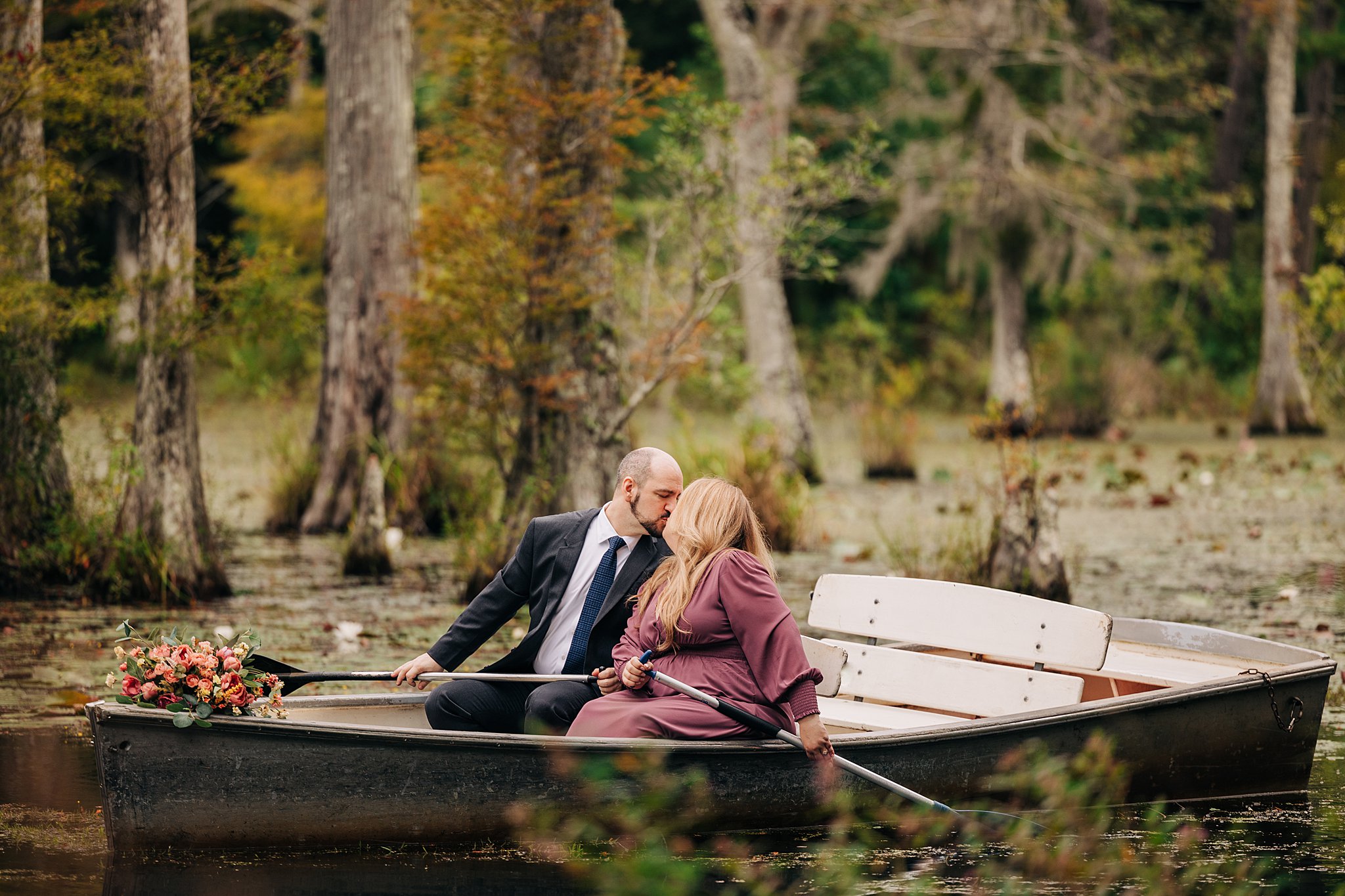 A newly engaged couple kiss mid paddle while in a boat celebrating their cypress gardens wedding engagement