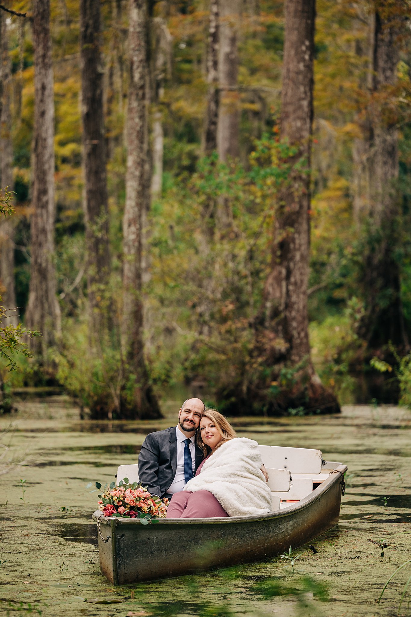 A newly engaged couple cuddle in a small boat in the swamp at their cypress gardens wedding engagement