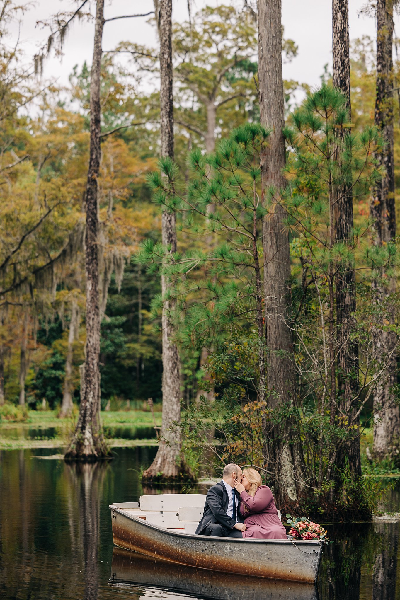 A couple kisses to celebrate their engagement in a boat floating in a calm swamp