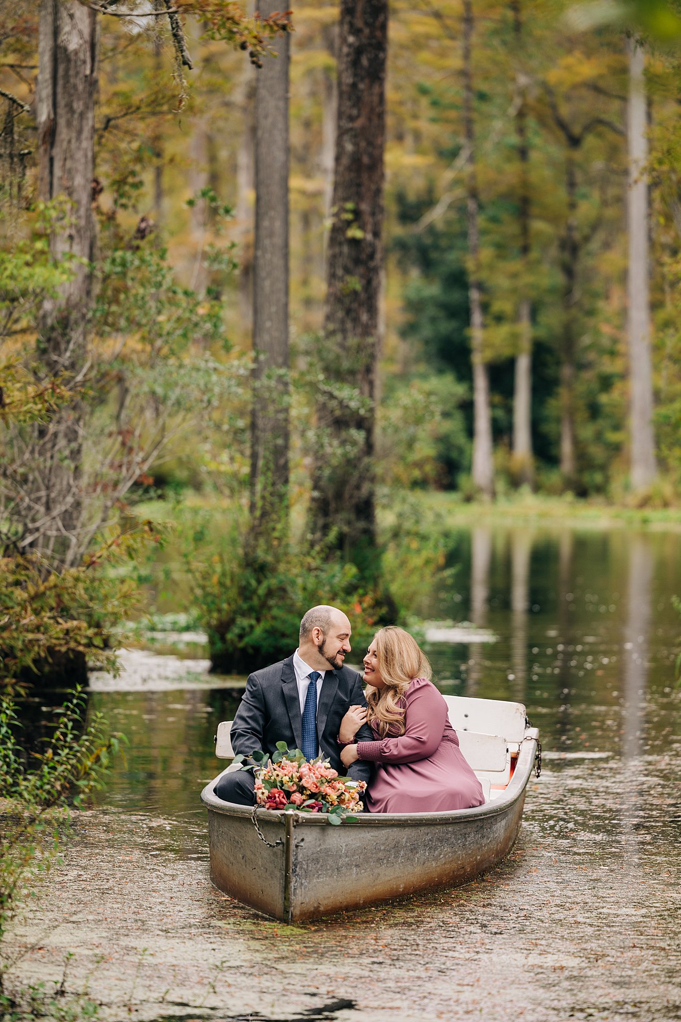 A couple snuggle while floating in a small boat in a swamp