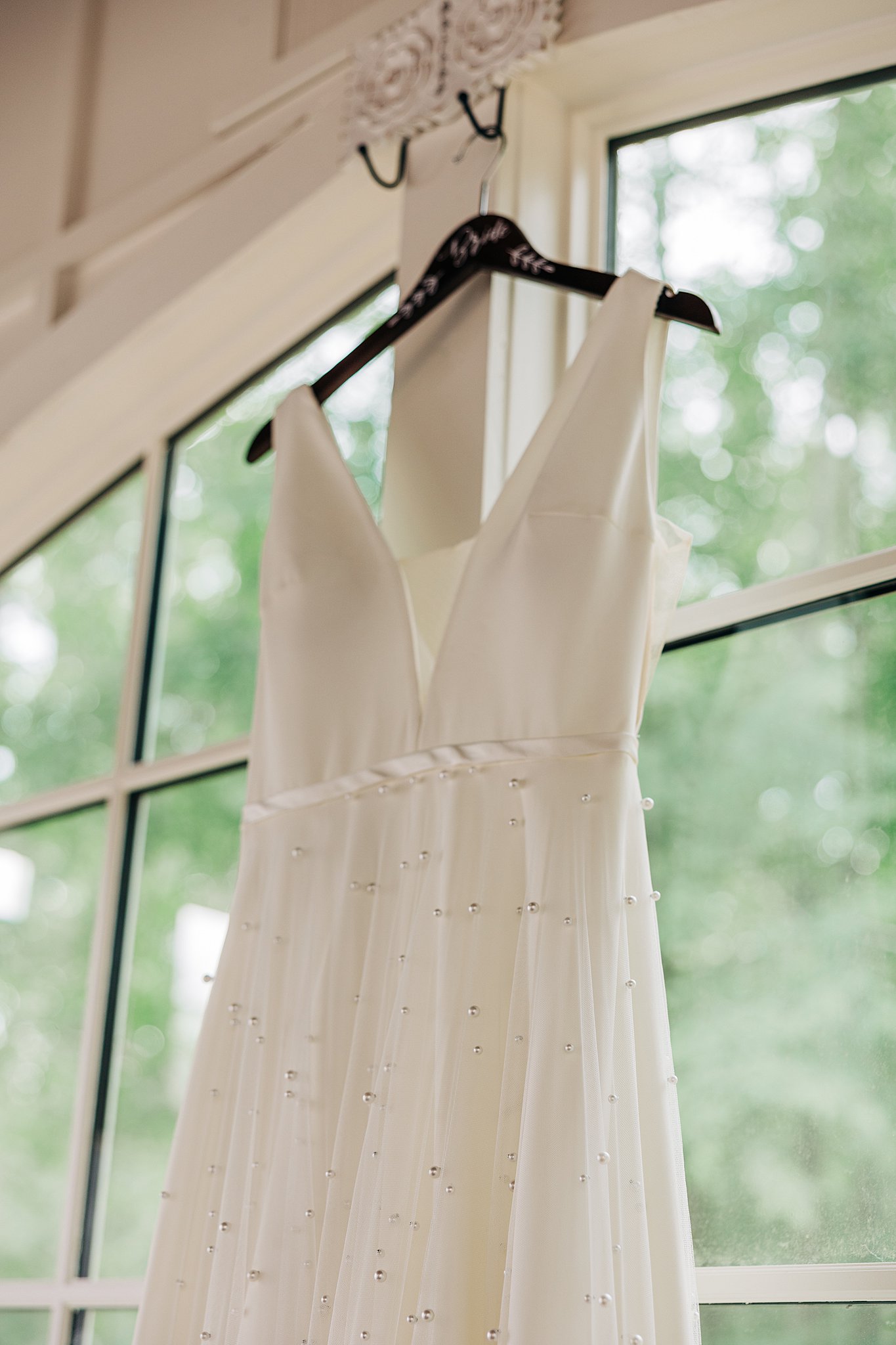Details of a wedding dress hanging from a window