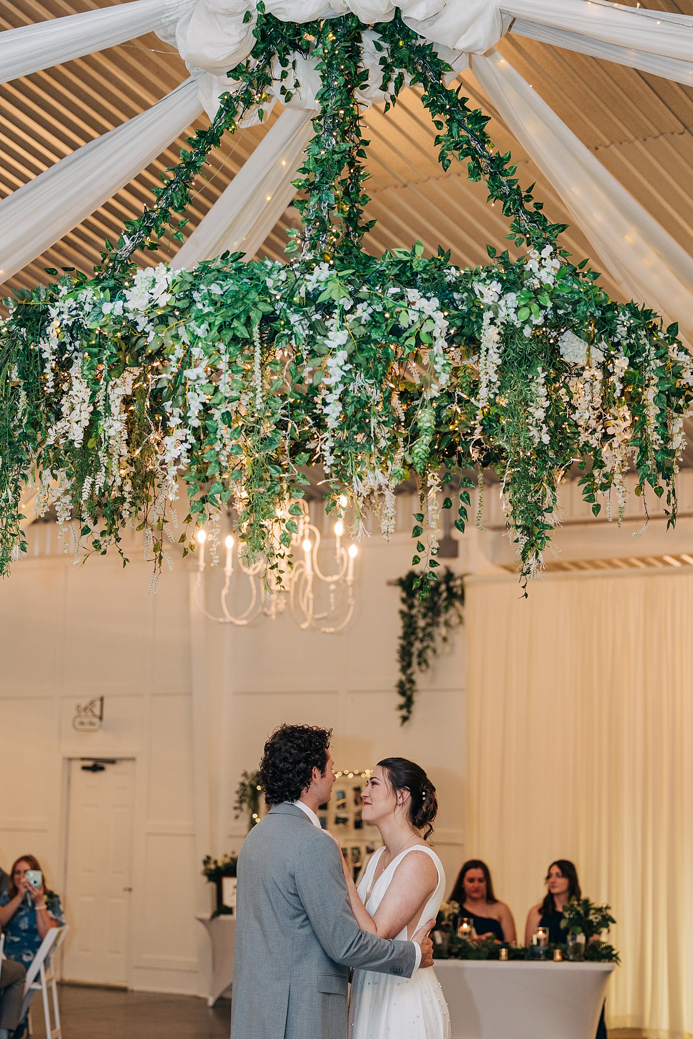 Newlyweds dance under a large living chandelier at their pinehill pavilion wedding