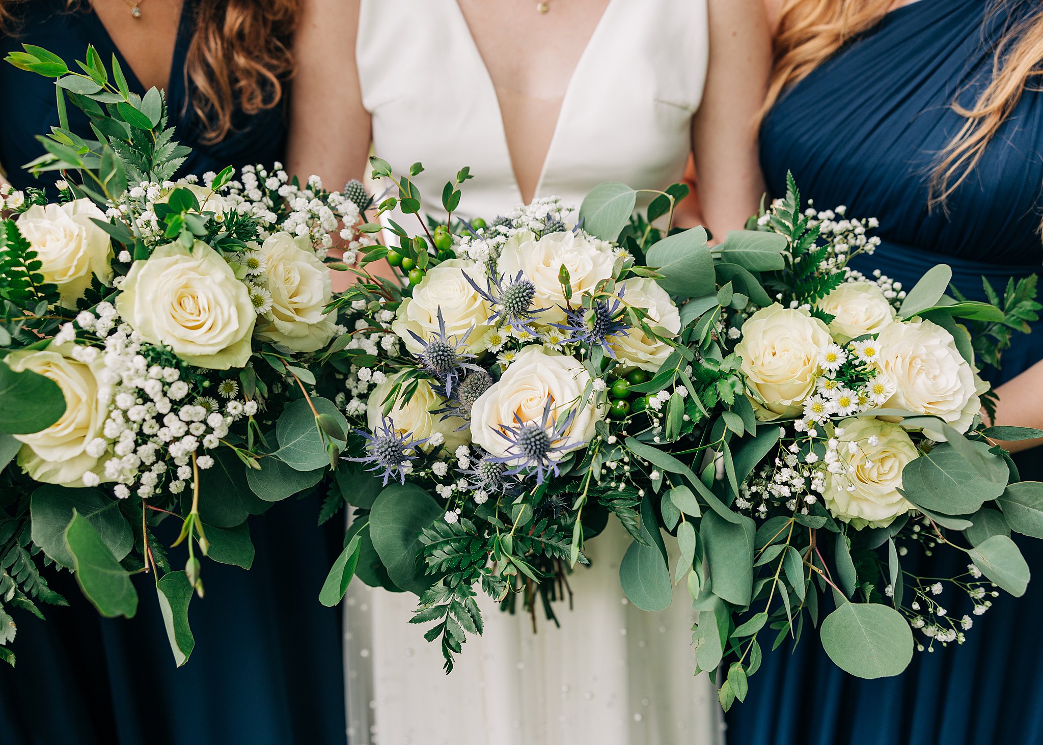 Details of a bride's white and blue bouquet with her bridesmaids