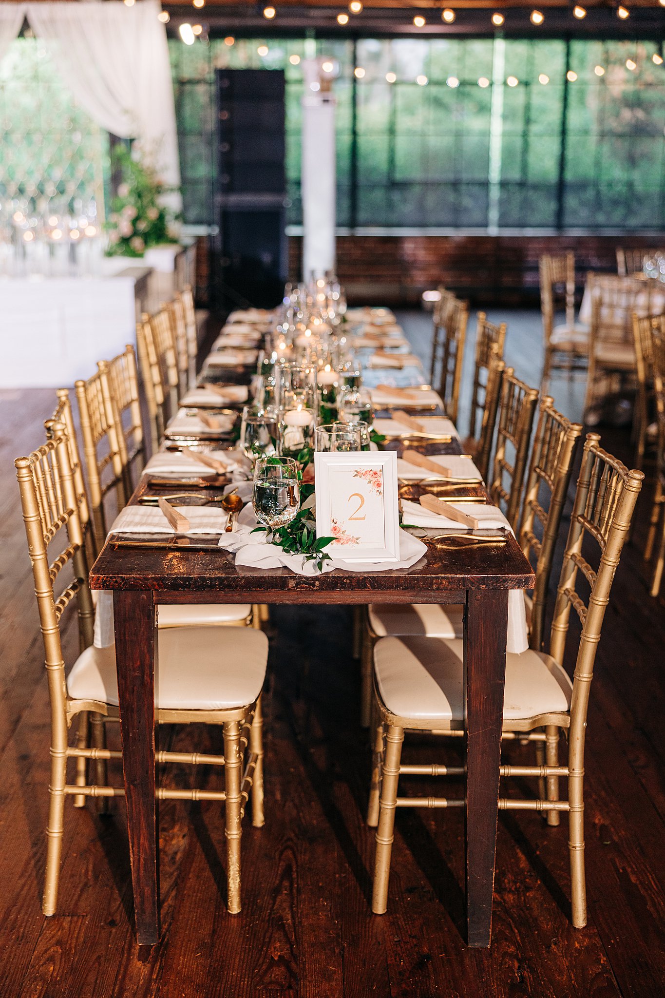 A long wedding reception table set up with gold chairs