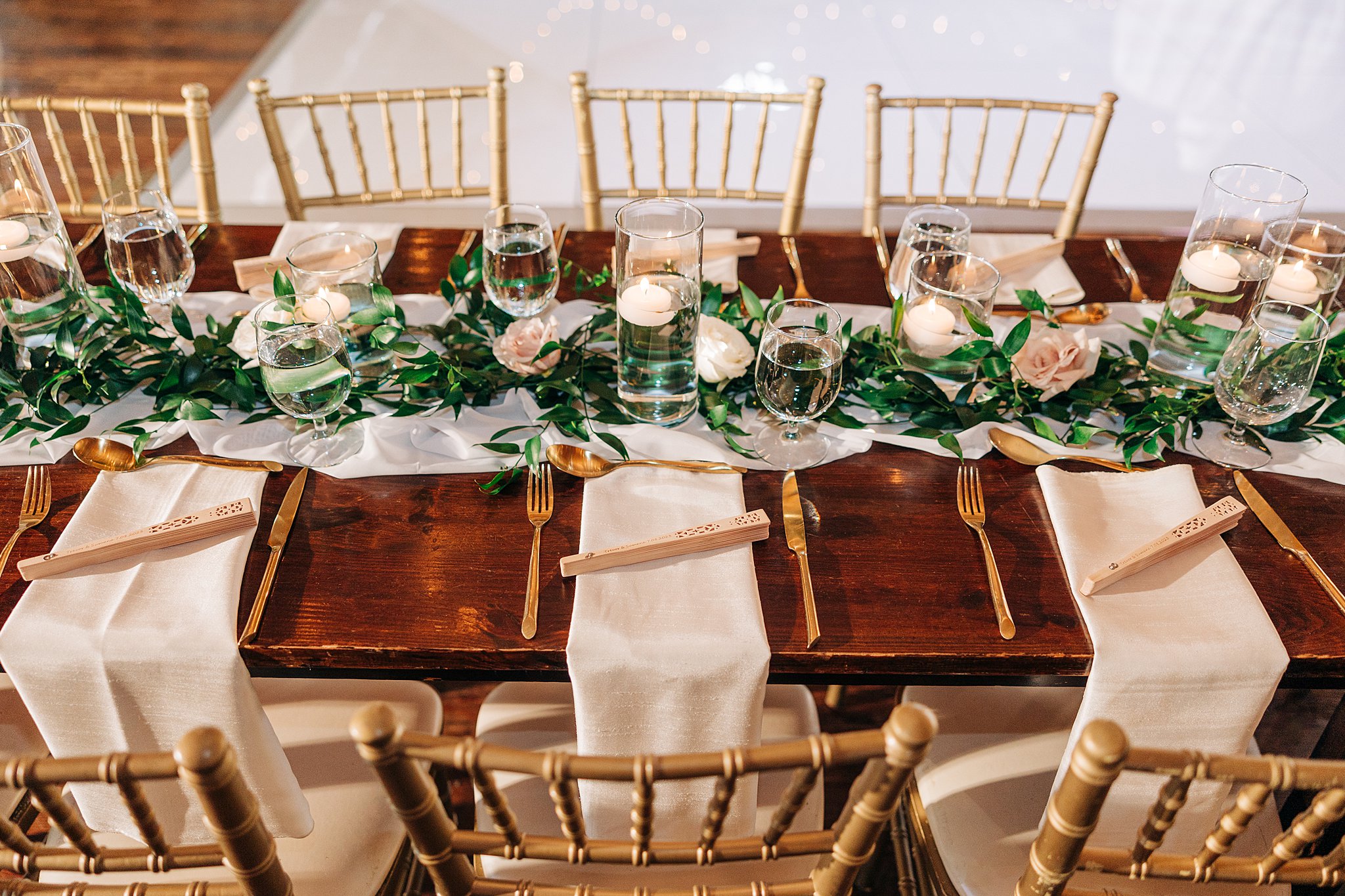 Details of a wooden wedding reception table set up with fans at each setting