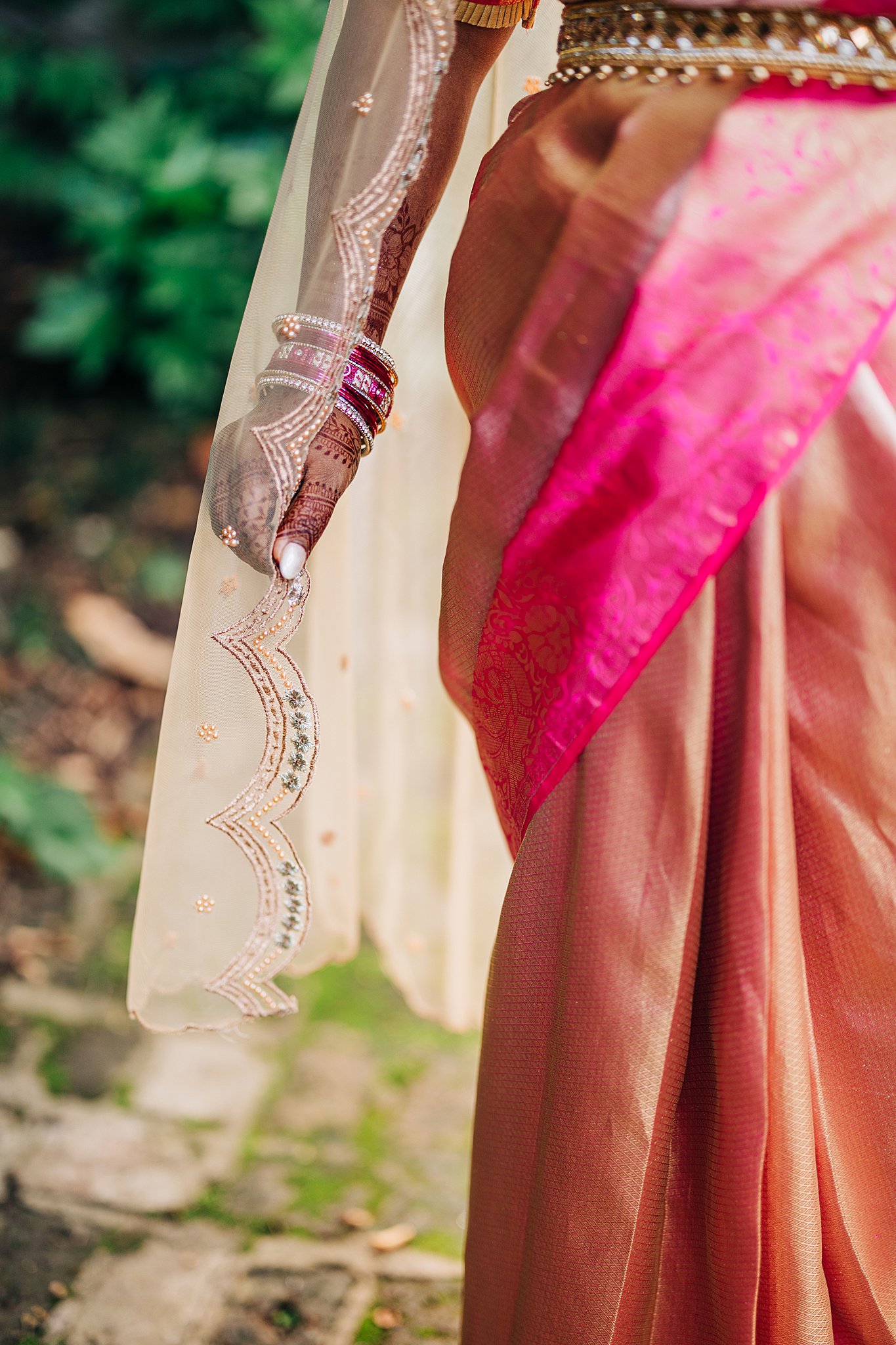 Details of a bride's henna covered hand holding her veil