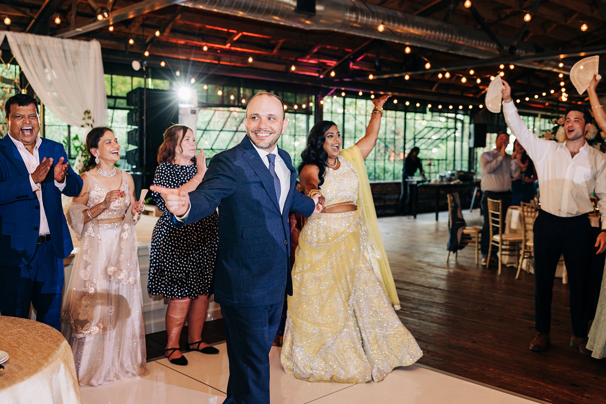 Newlyweds enter their reception to cheers and celebration at their summerour studio wedding reception