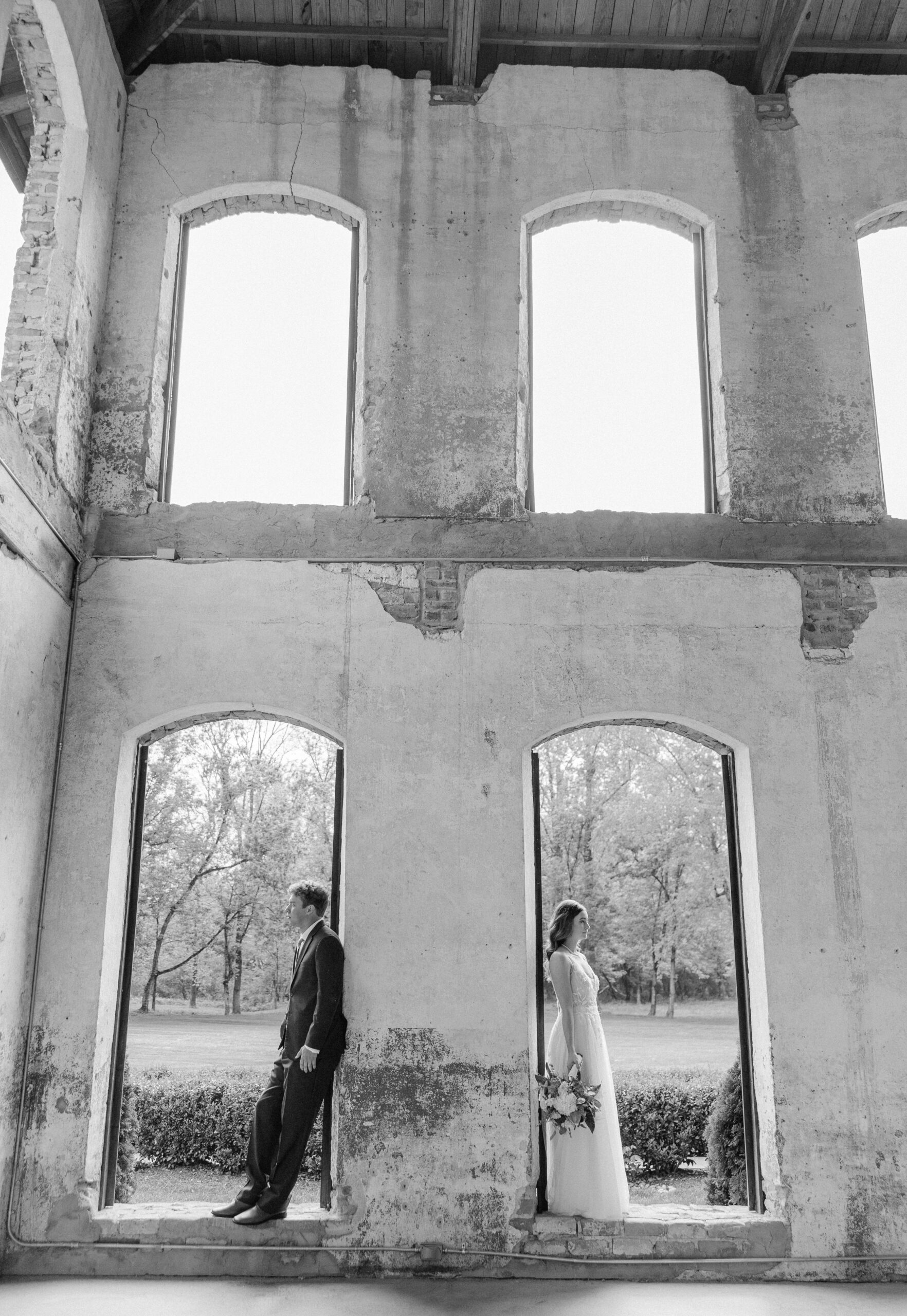 Newlyweds stand in individual window openings at the Providence Cotton Mill wedding venue