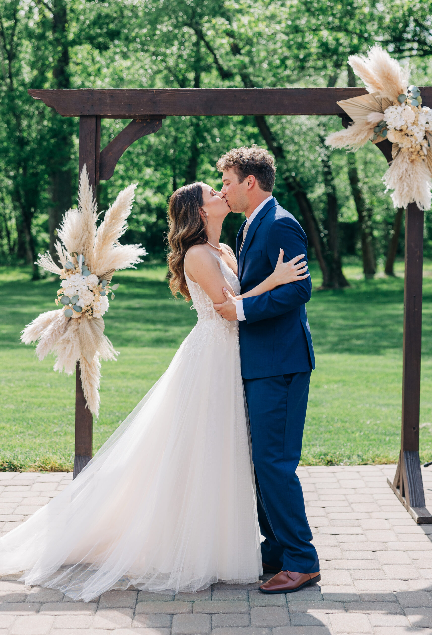 Newlyweds kiss under their outdoor wooden wedding arbor