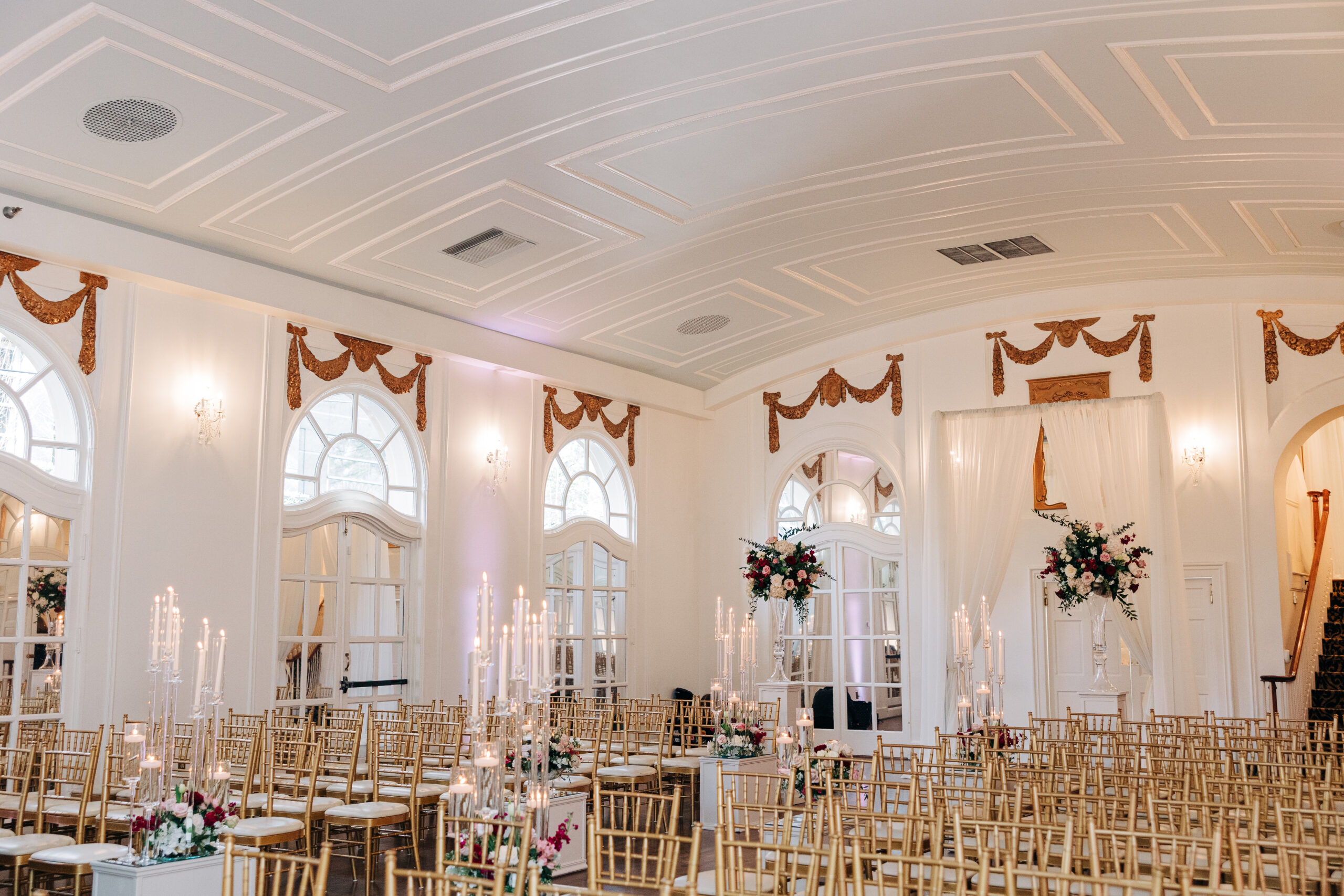 A Wimbish House wedding ceremony set up with gold chairs and many candles