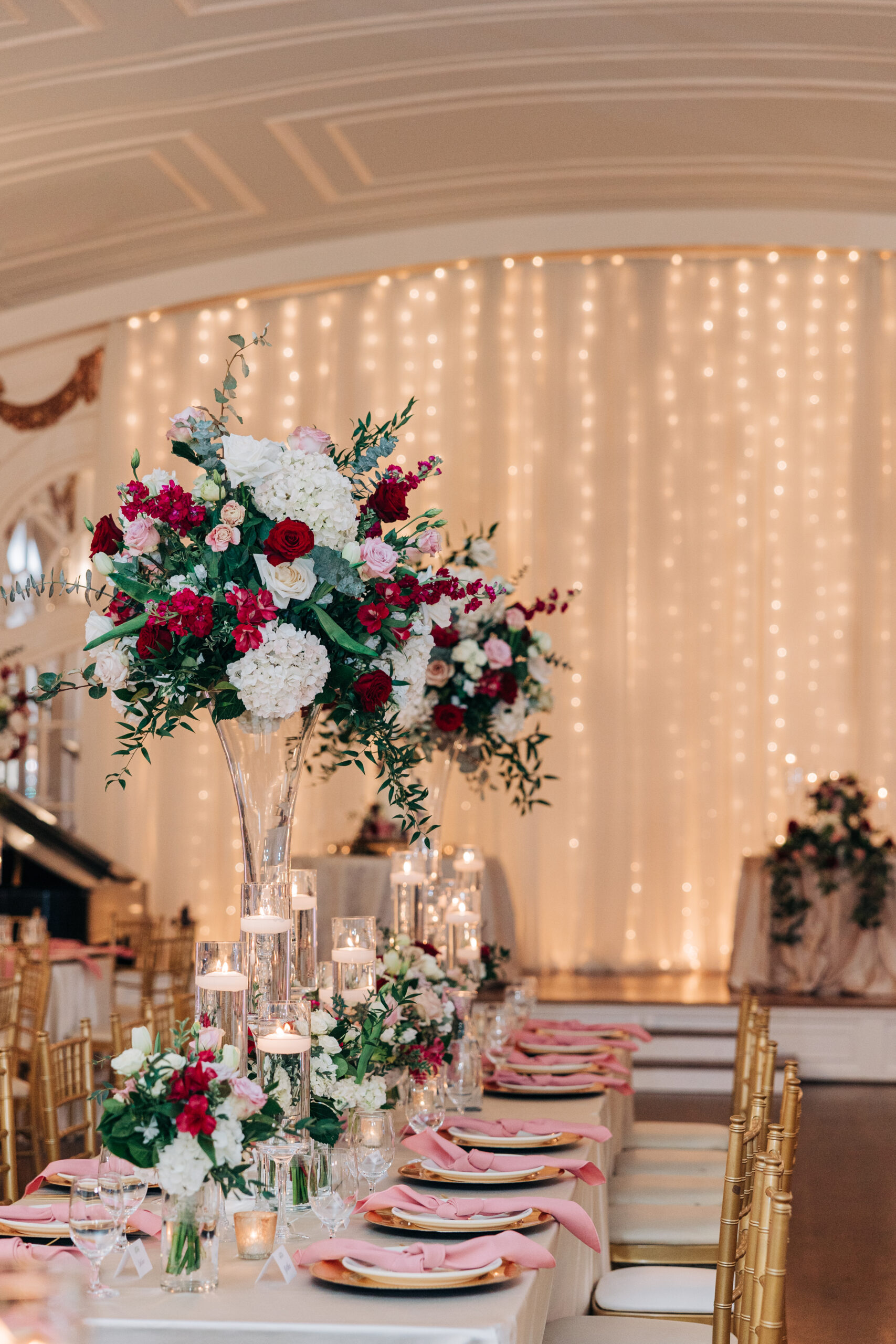 Details of a Wimbish House wedding reception table with tall floral centerpieces and gold chairs