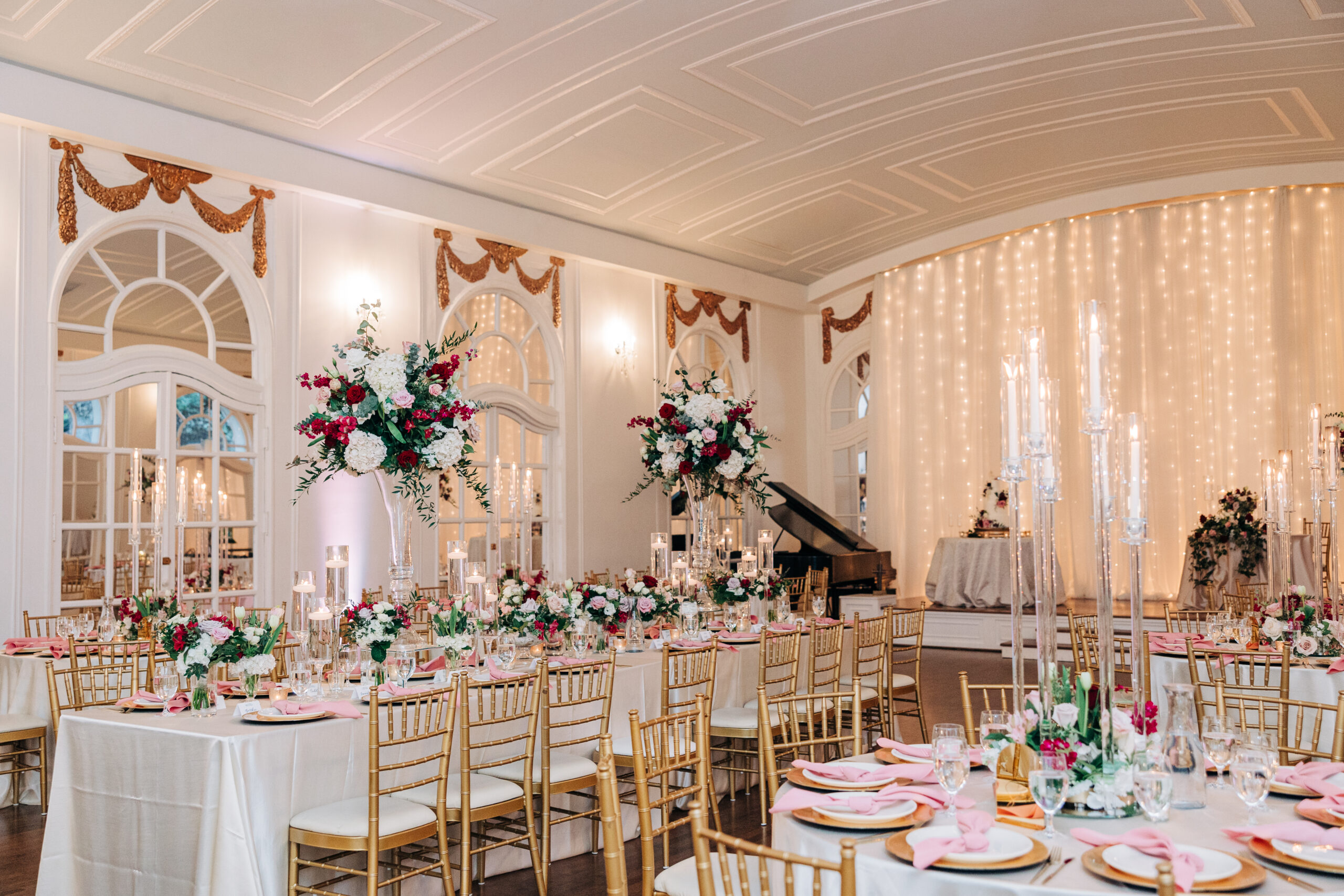 A Wimbish House wedding reception set up with large florals, pink napkins and gold chairs