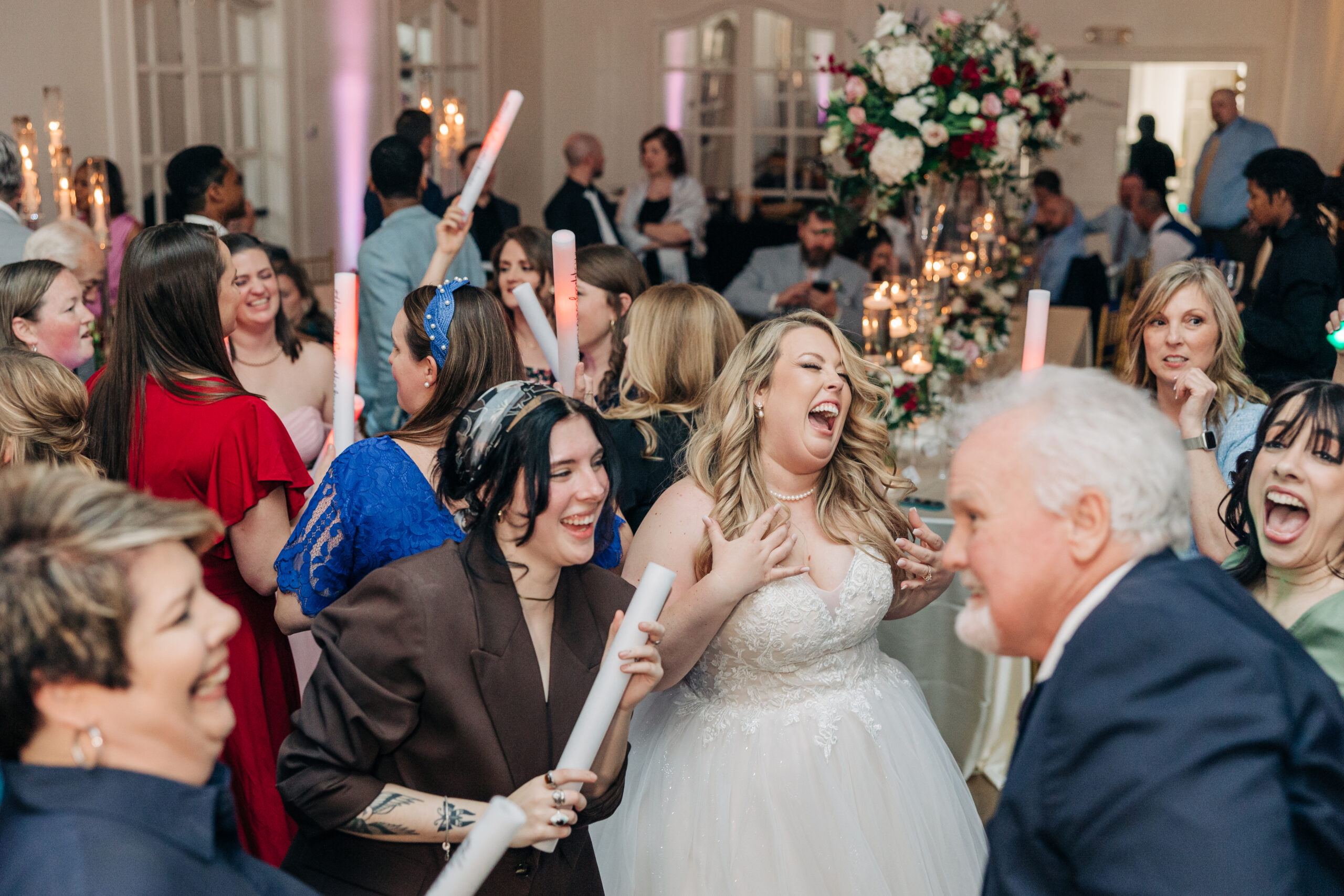 A bride sings and dances surrounded by friends during her Wimbish House wedding reception