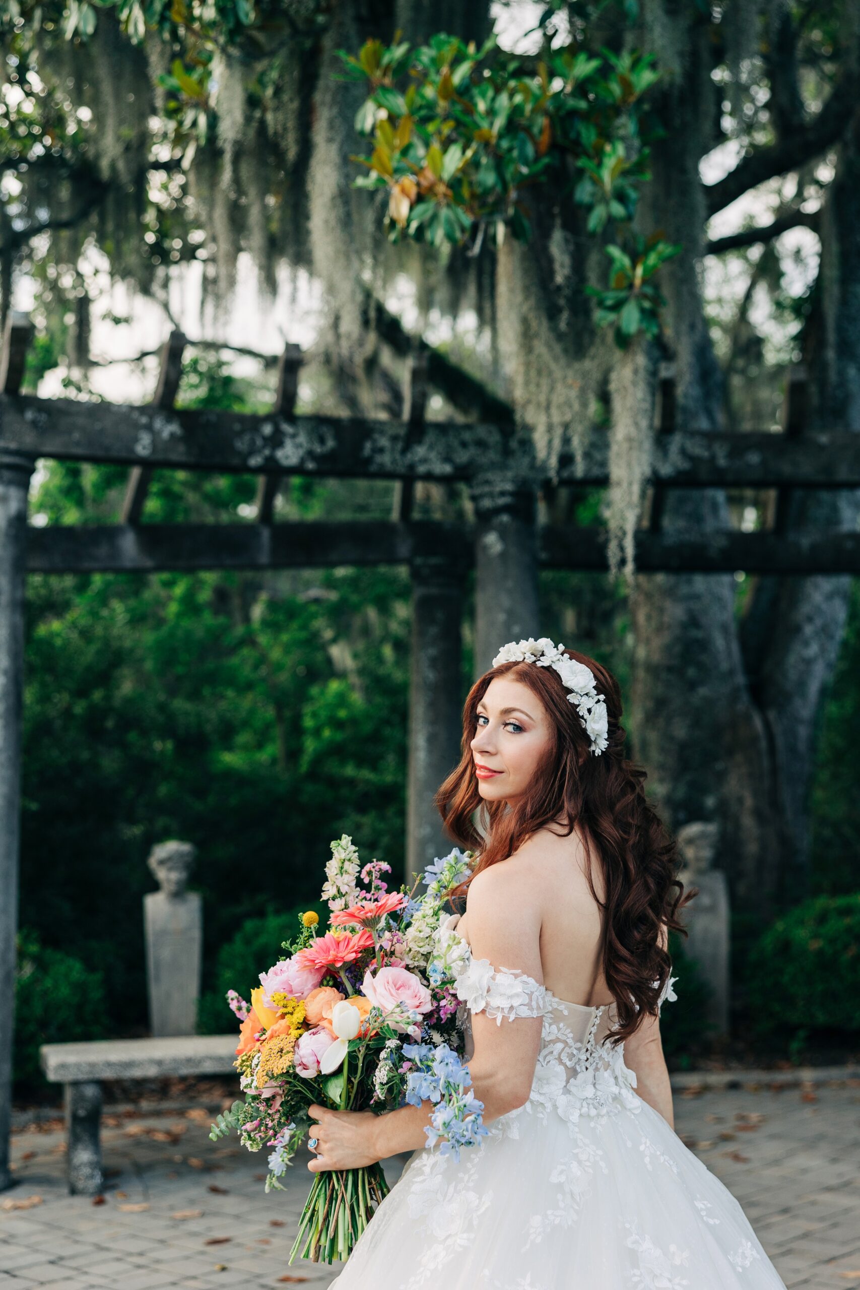 A bride smiles over her shoulder while walking in a beautiful Airlie Gardens wedding