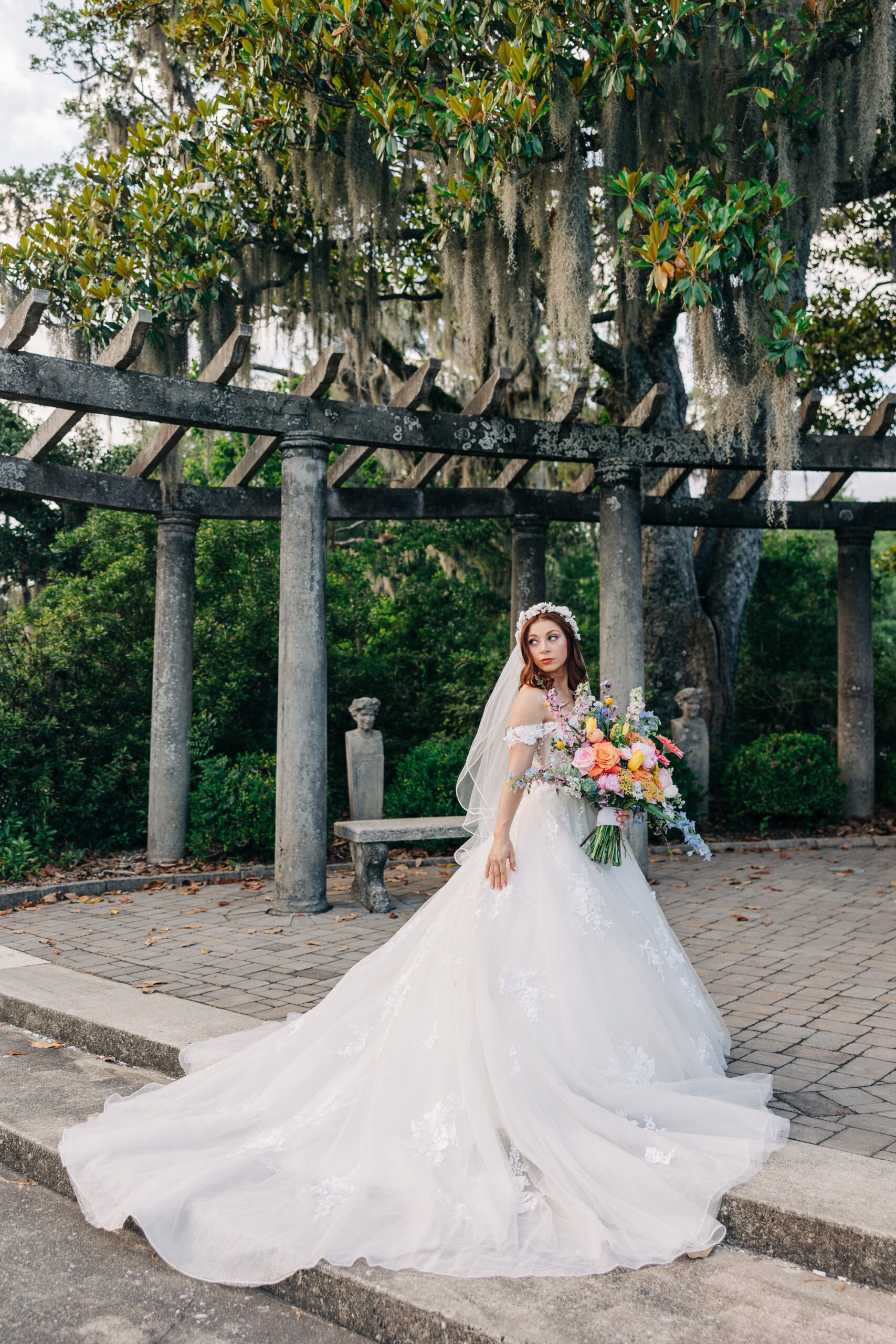 A bride walks into the Airlie Gardens wedding gazebo holding her bouquet and looking over her shoulder