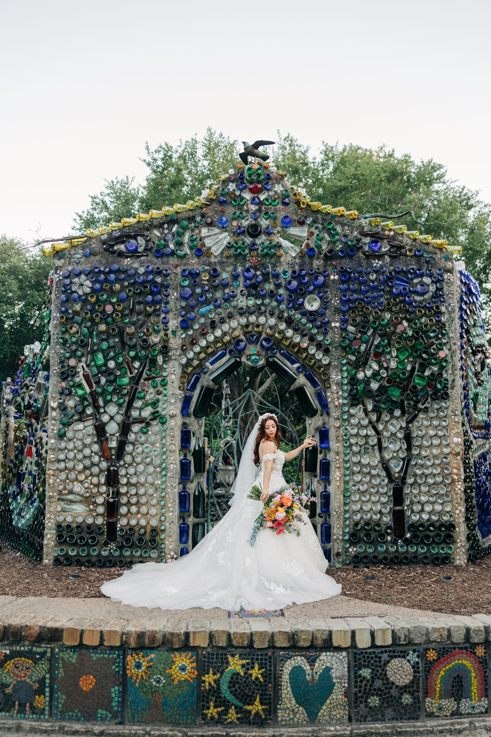 A bride leans on a glass sculpture wall at her Airlie Gardens wedding