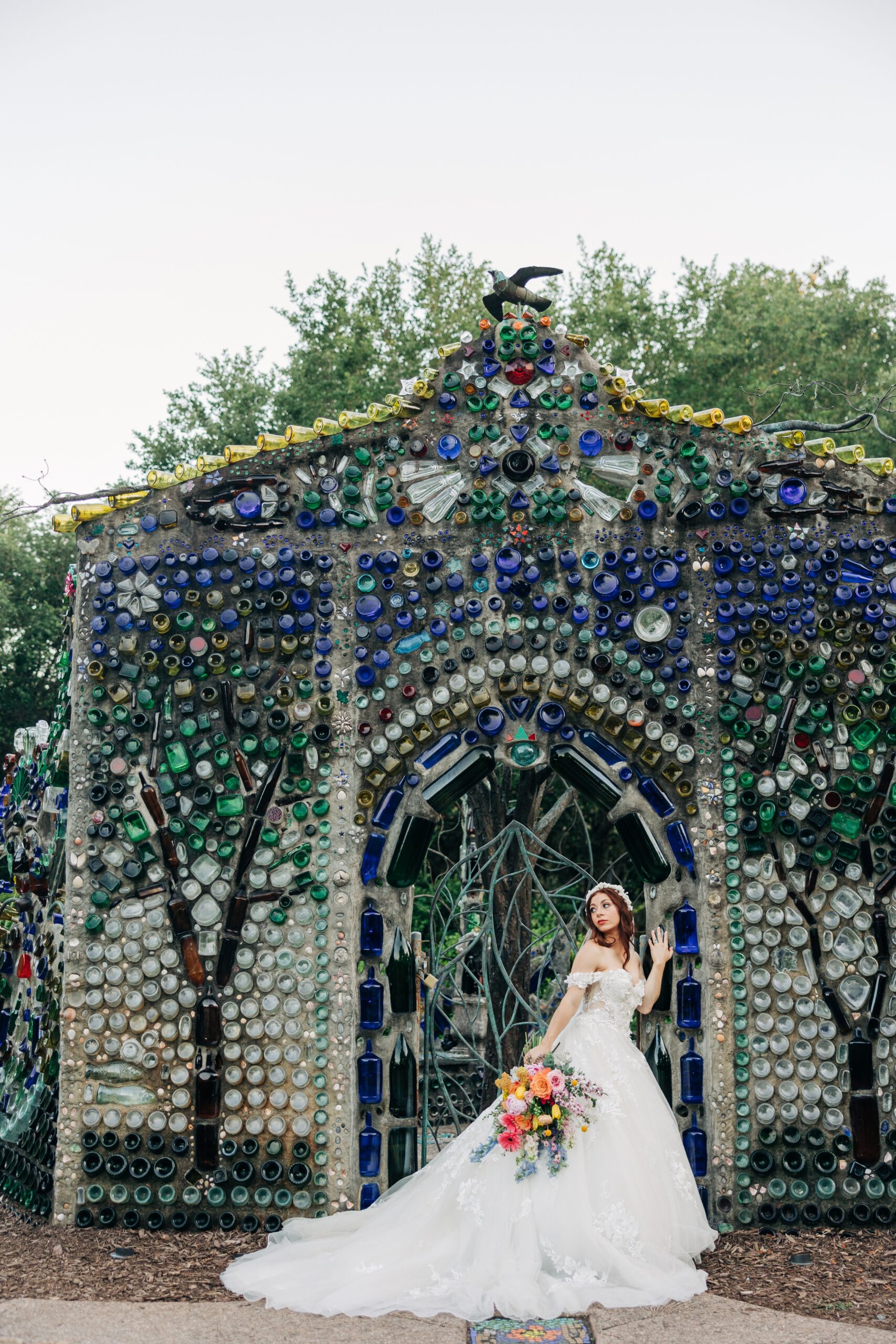 A bride walks in front of a glass sculpture wall at her Airlie Gardens wedding