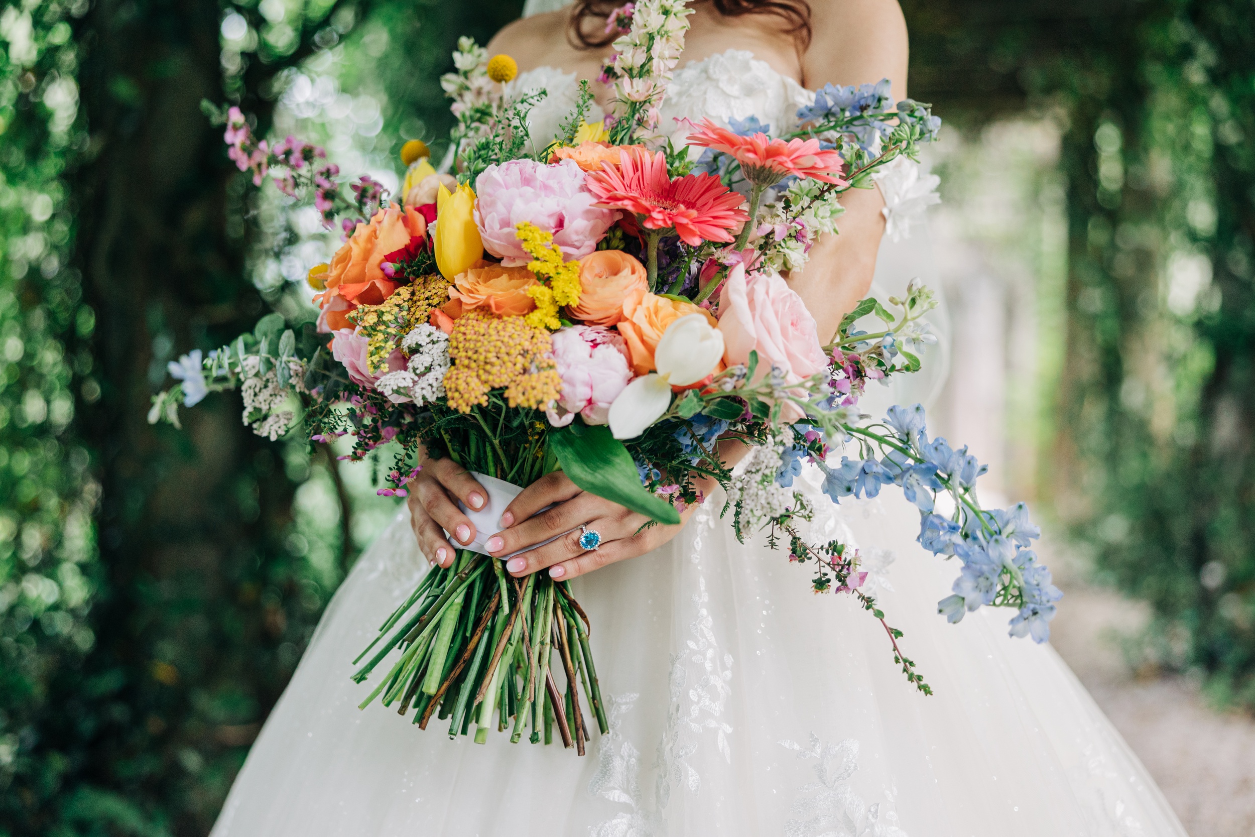 Details of a bride holding her colorful and vibrant bouquet in a garden