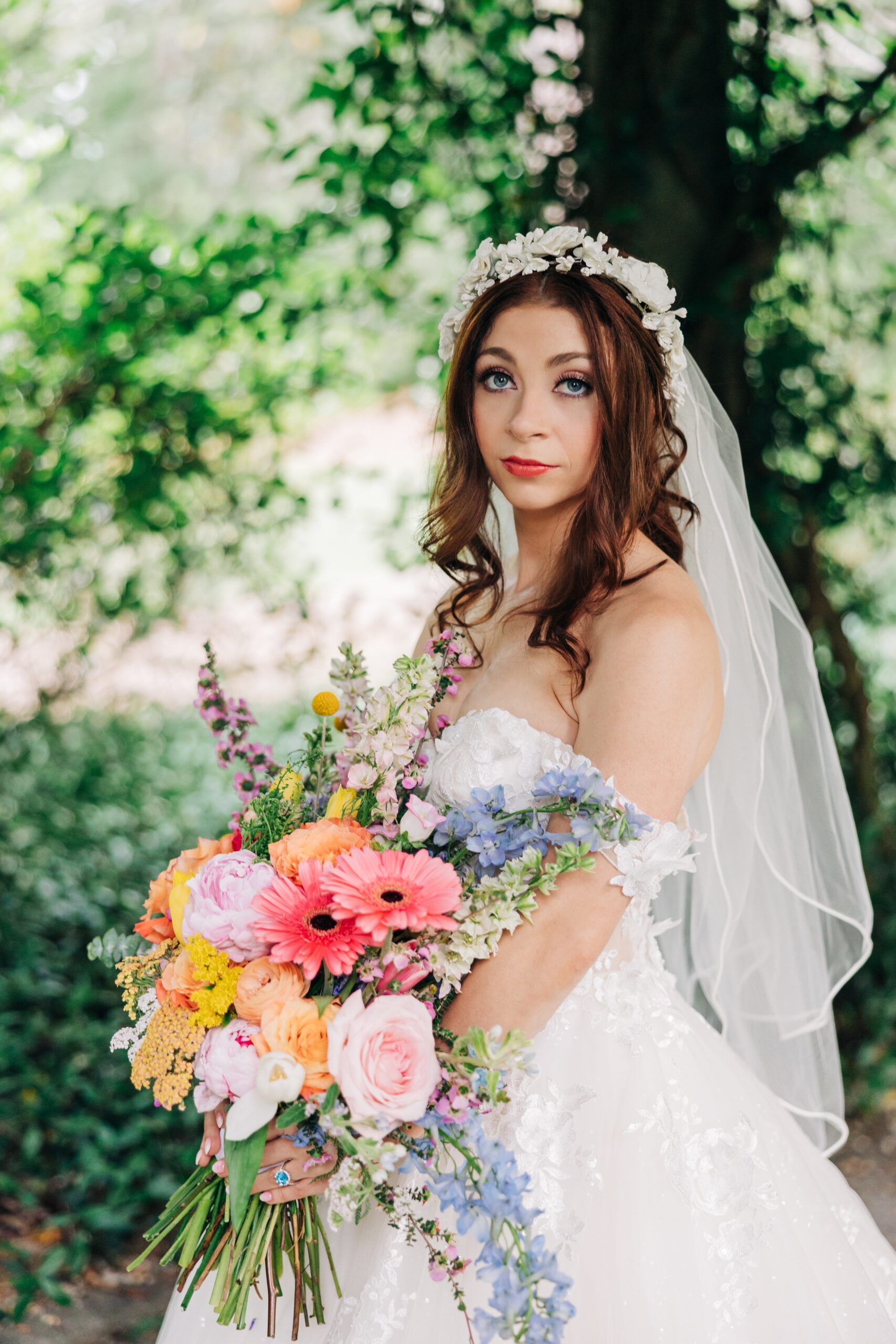 A bride looks out to the sunset while holding her vibrant bouquet