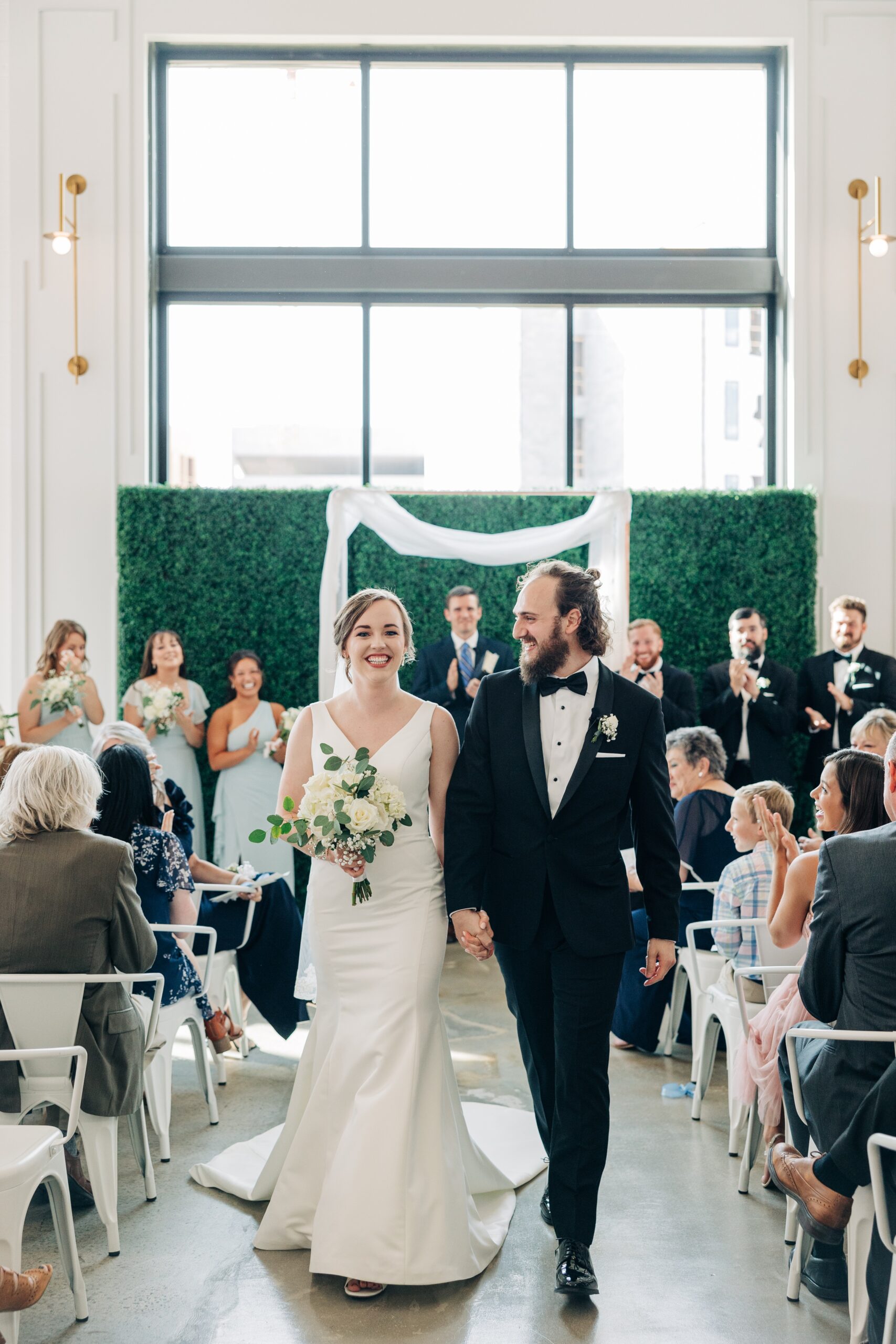 Newlyweds smile while exiting their pine wedding venue ceremony up the aisle