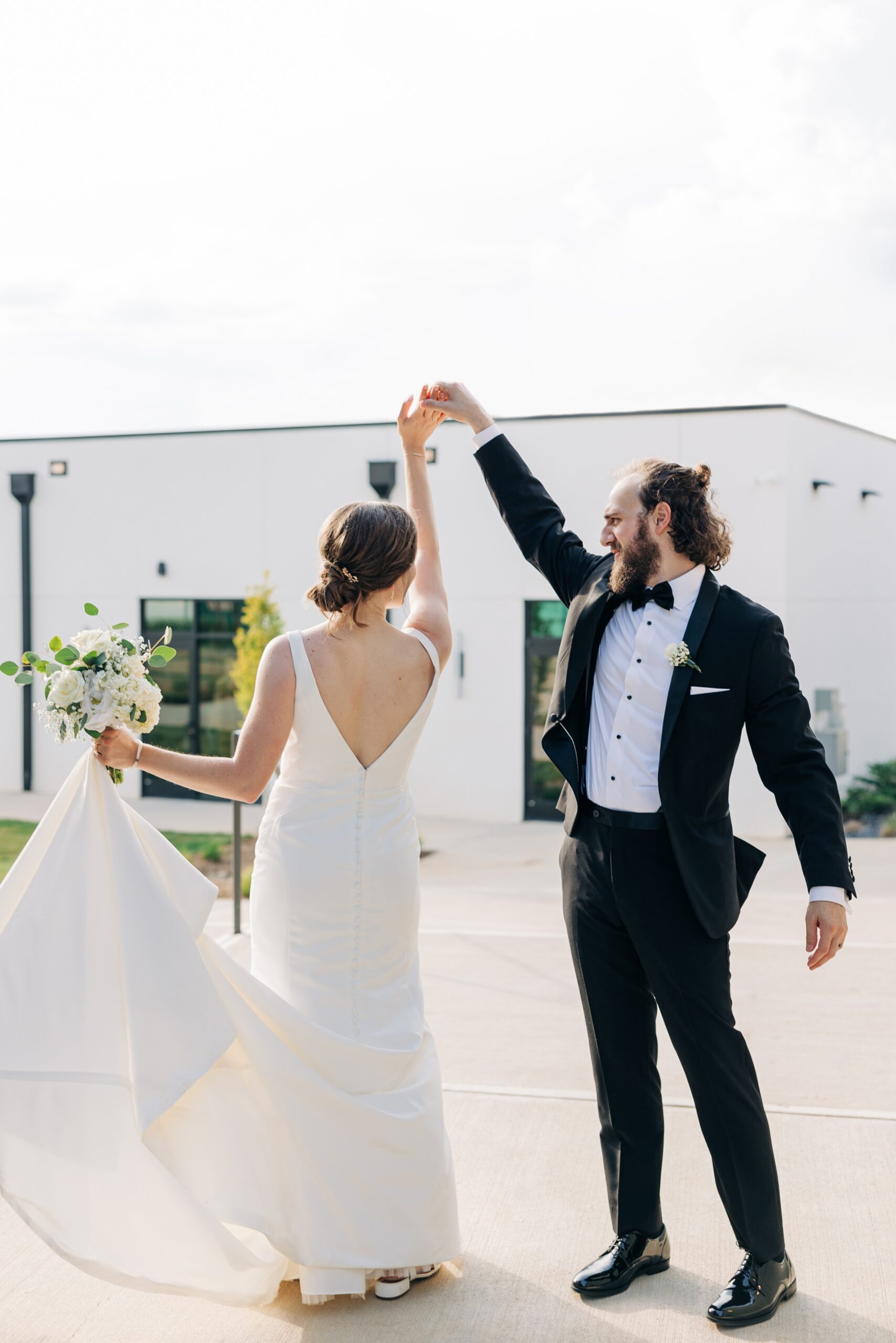 A groom twirls his bride while dancing on a patio at the pine wedding venue