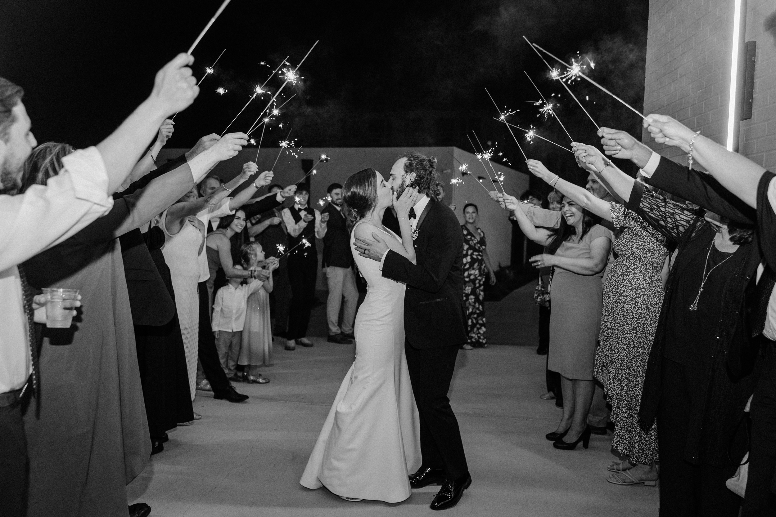 Newlyweds kiss under a sparkler arch during their exit from the pine wedding venue