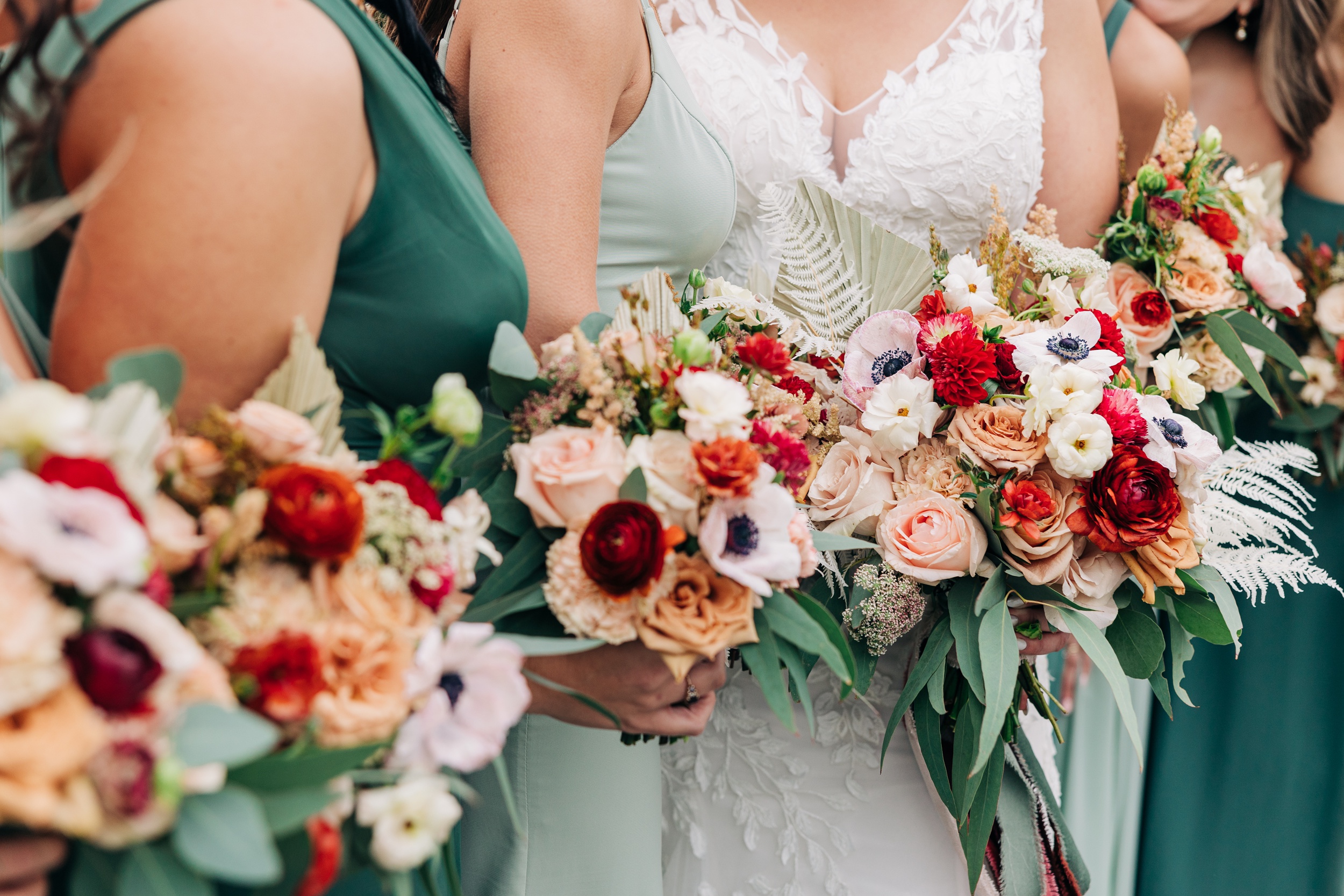 Details of a bride and her bridesmaids' bouquets in a line while holding them