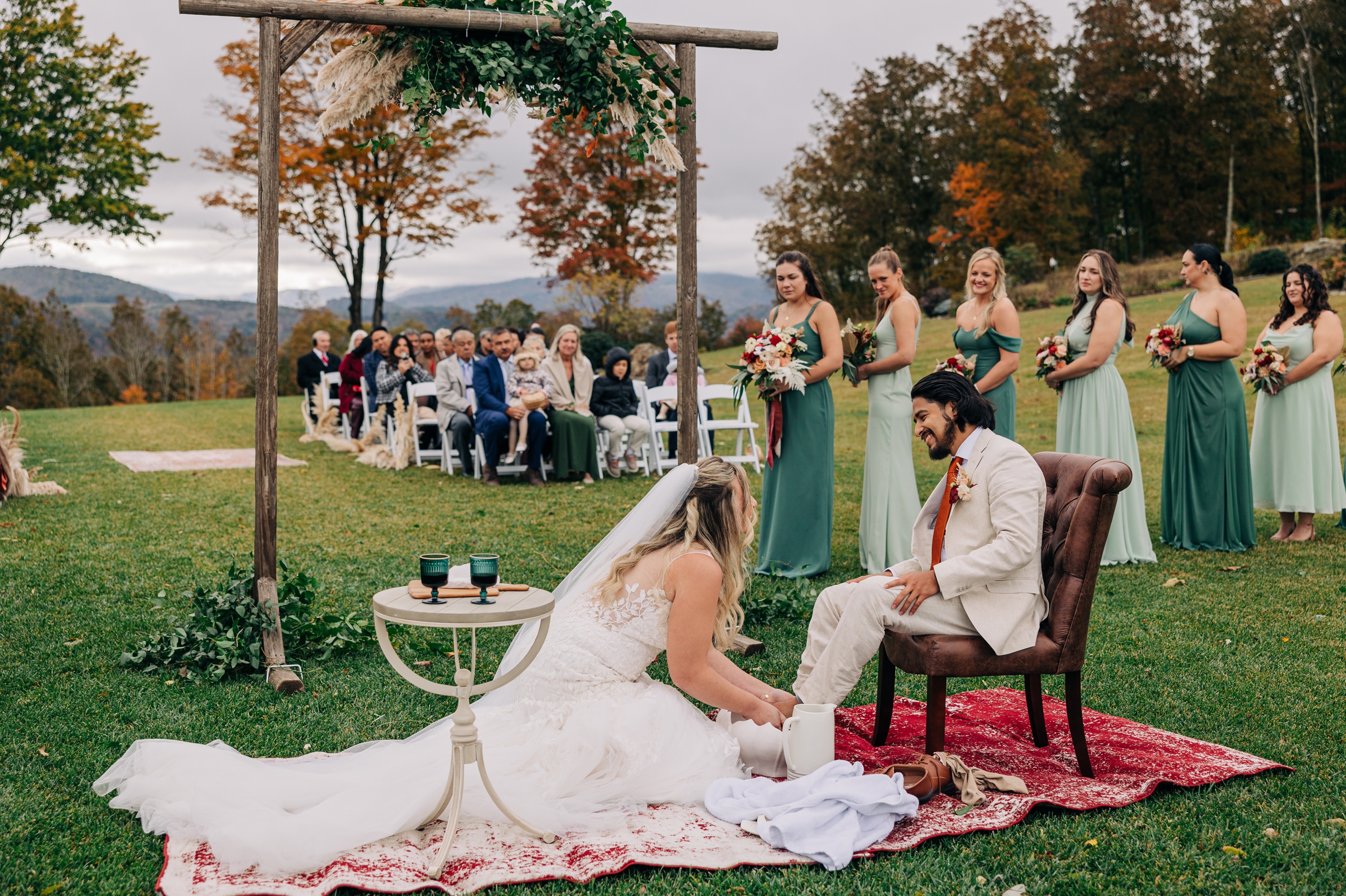 A bride washes the feet of her groom during their appalachian view wedding ceremony