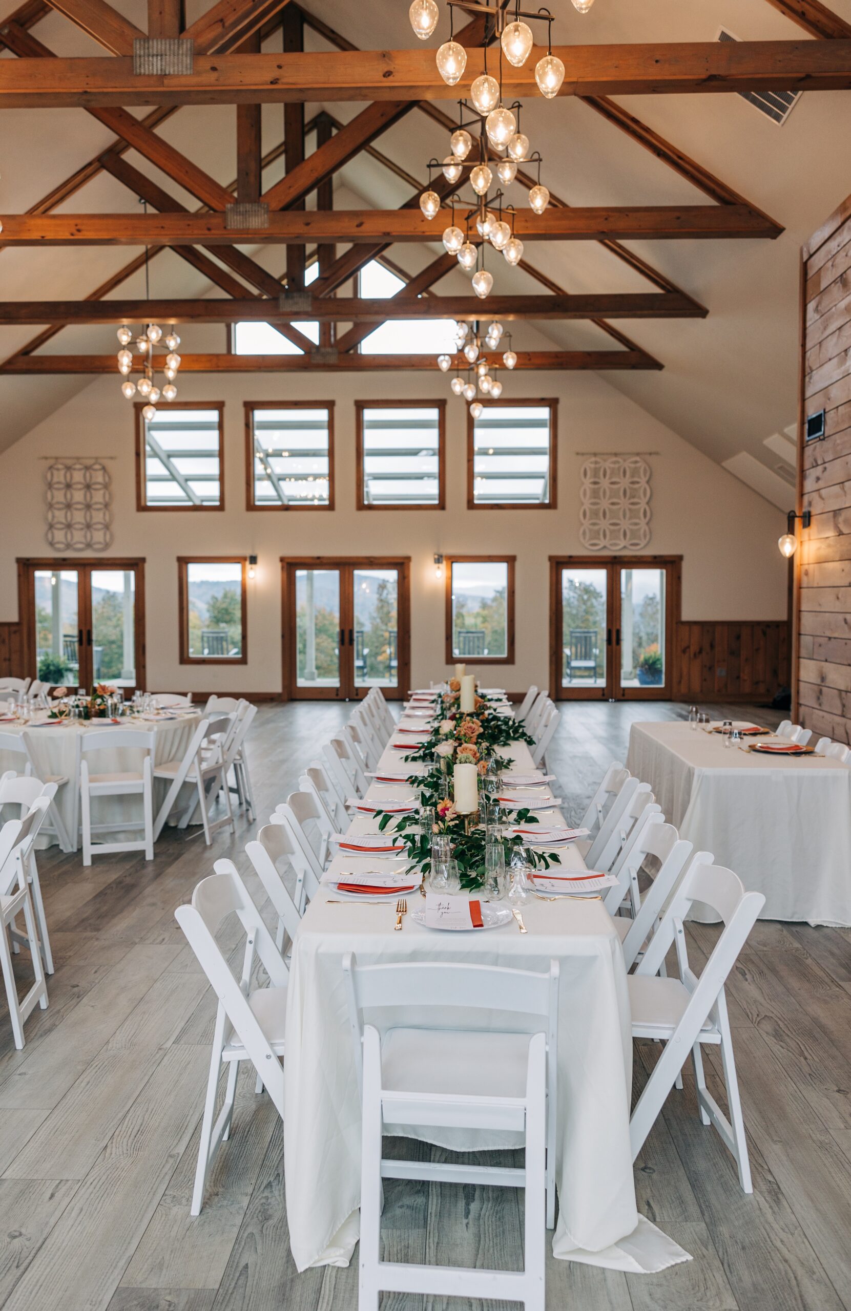 Details of a long white appalachian view wedding reception table set up under the wooden beams