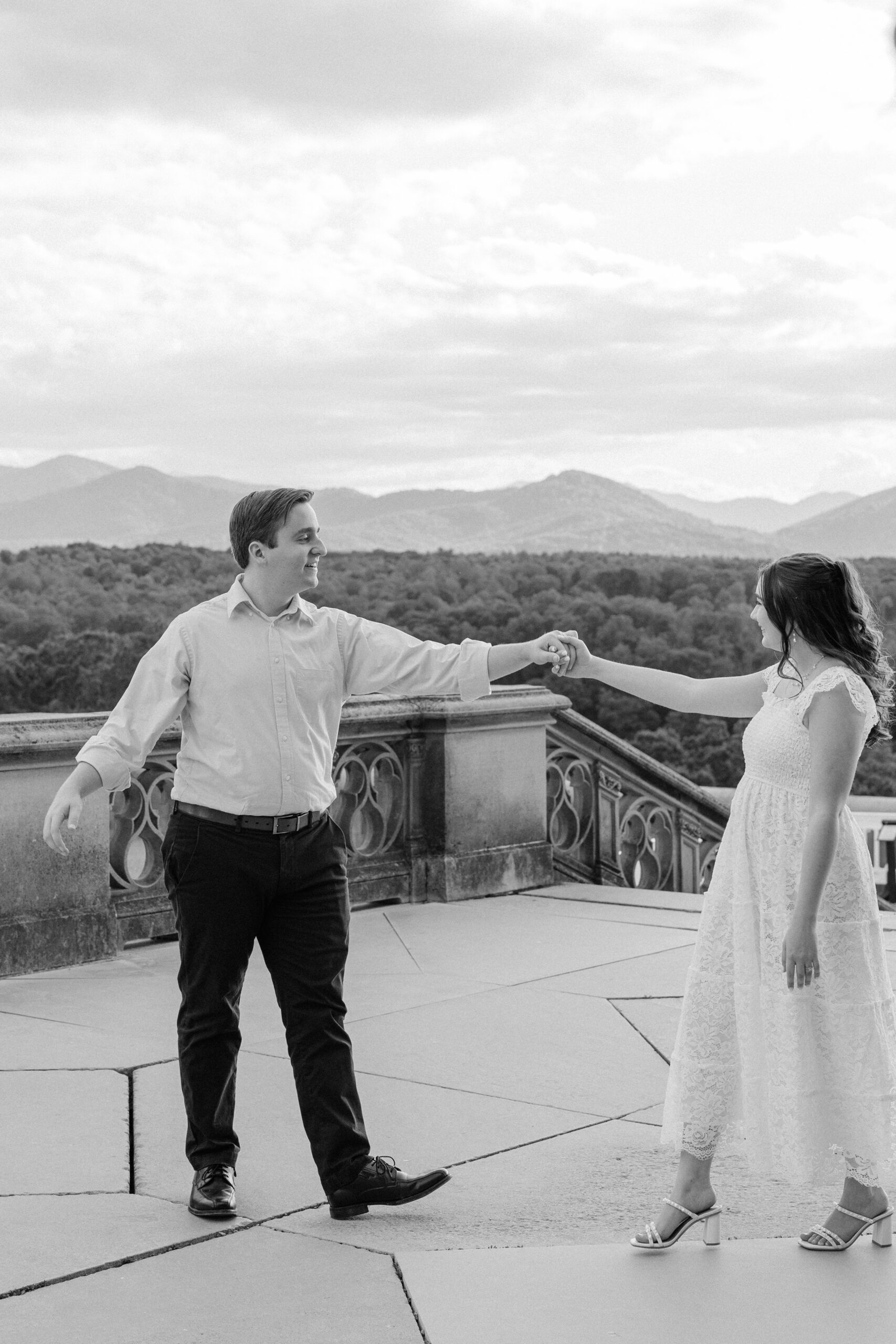 A bride and groom dance and spin on a patio in the mountains