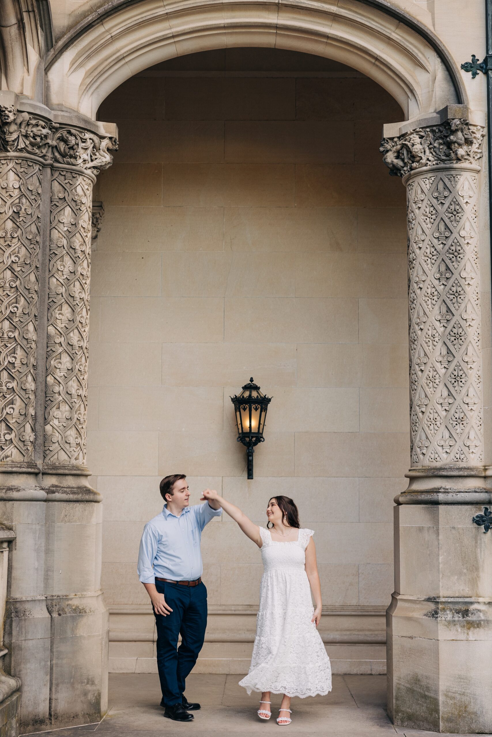 A groom twirls his dancing bride under an ornate archway