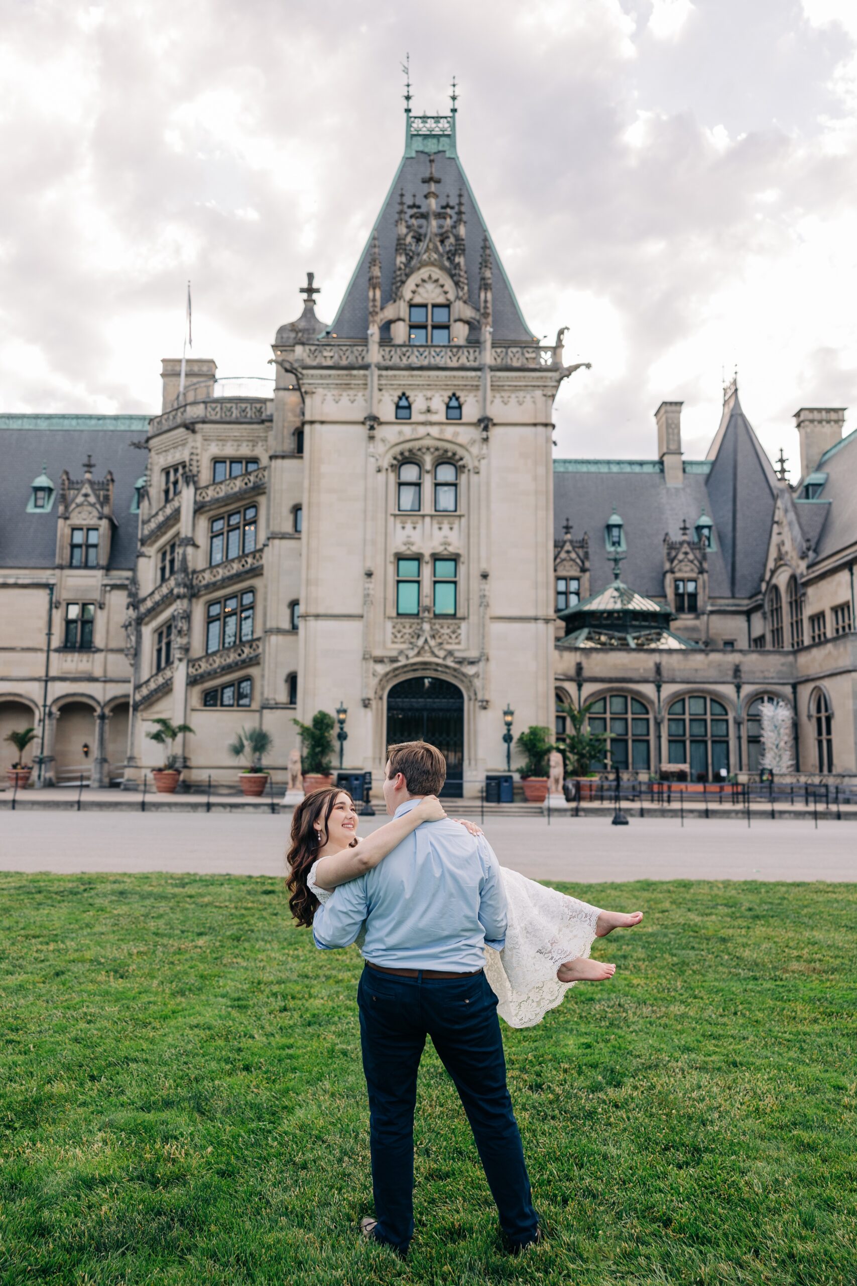 A groom carries his bride while walking in the lawn