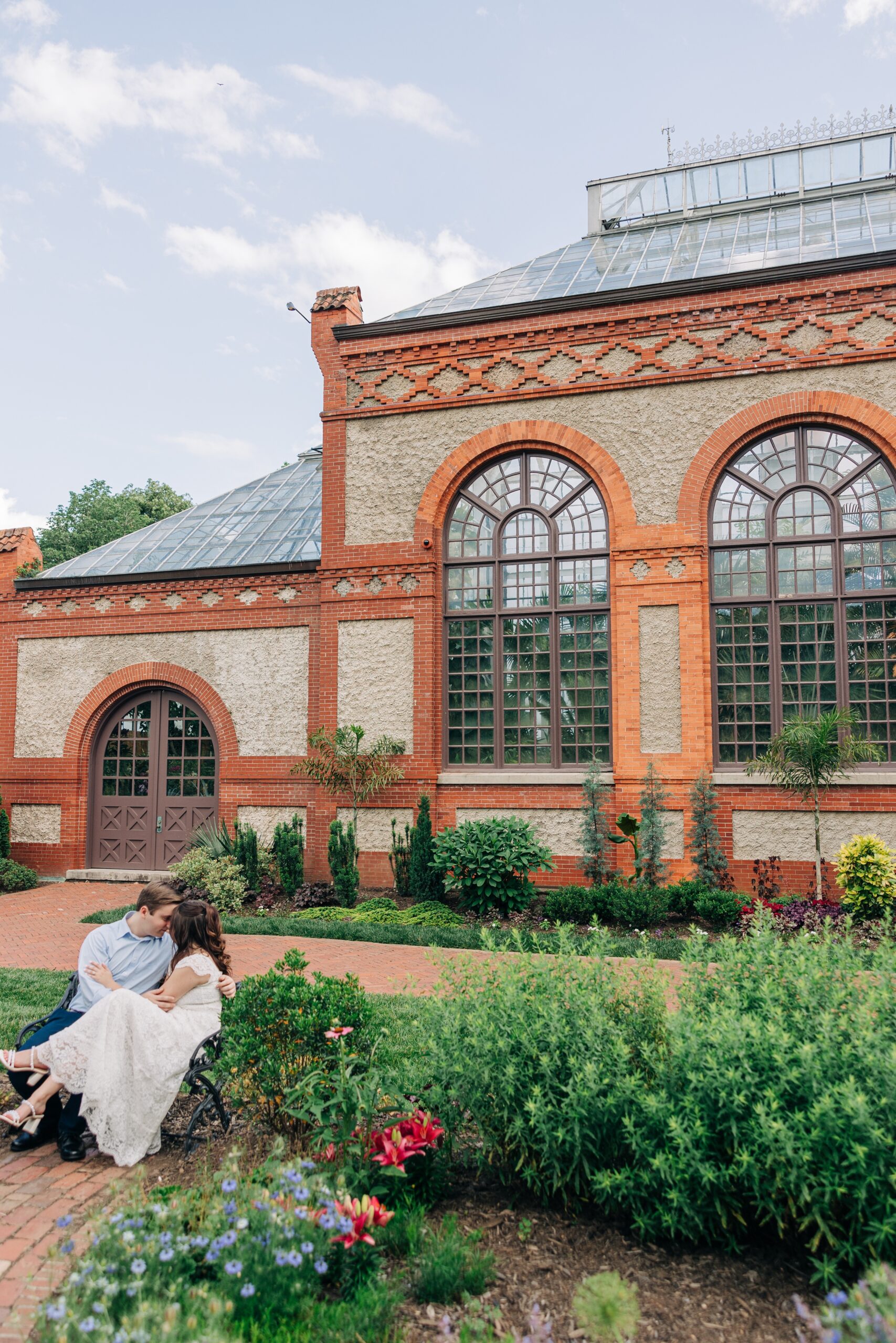 Newlyweds sit on a bench in the garden while touching foreheads during their biltmore estate wedding