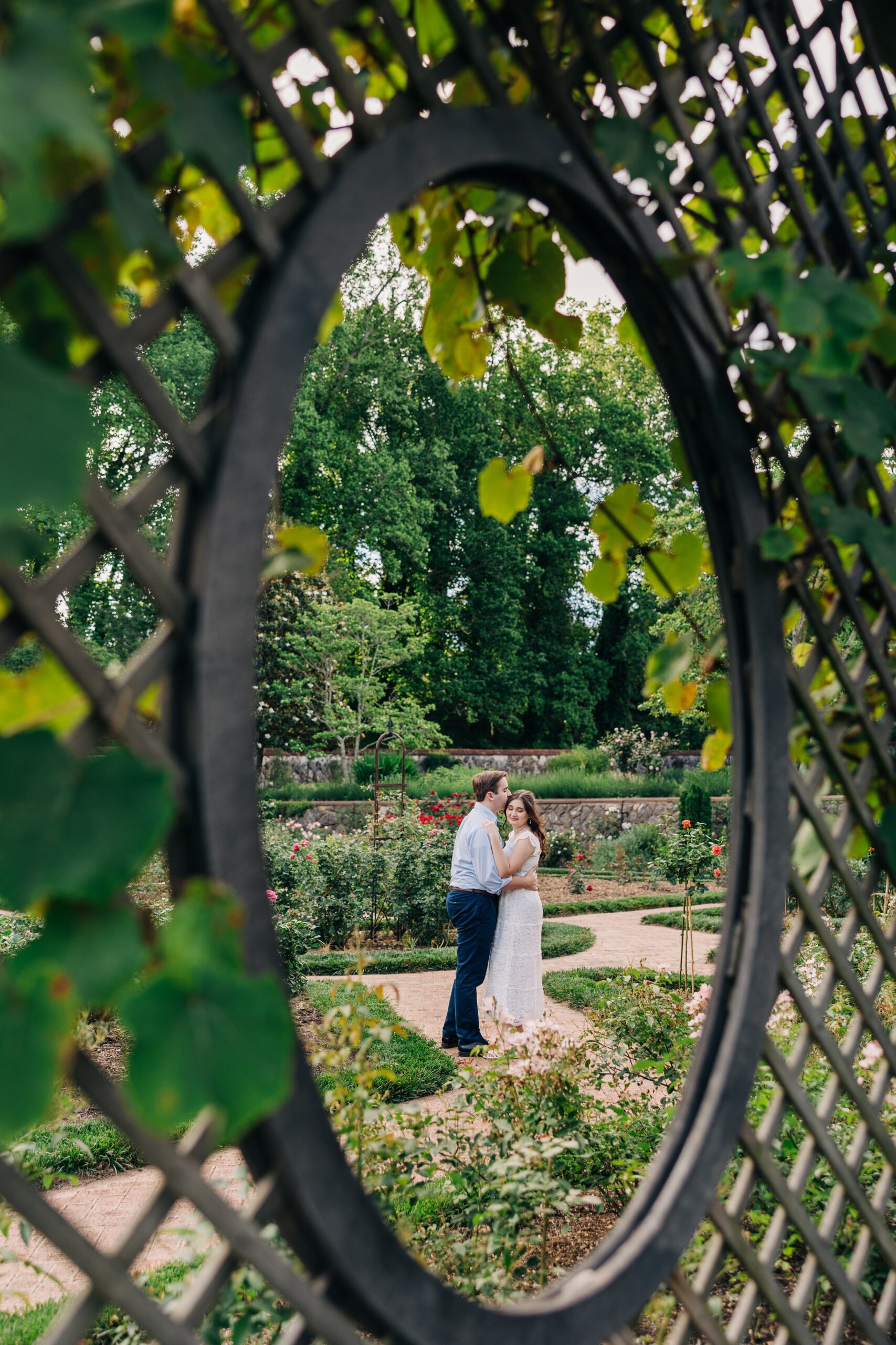 Newlyweds cuddle and kiss while standing in the biltmore estate wedding venue garden